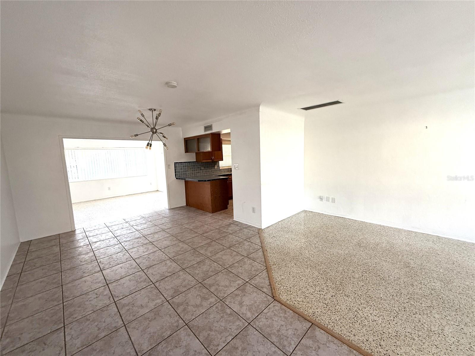 Living room on right and tiled dining area, looking toward kitchen from front entry.