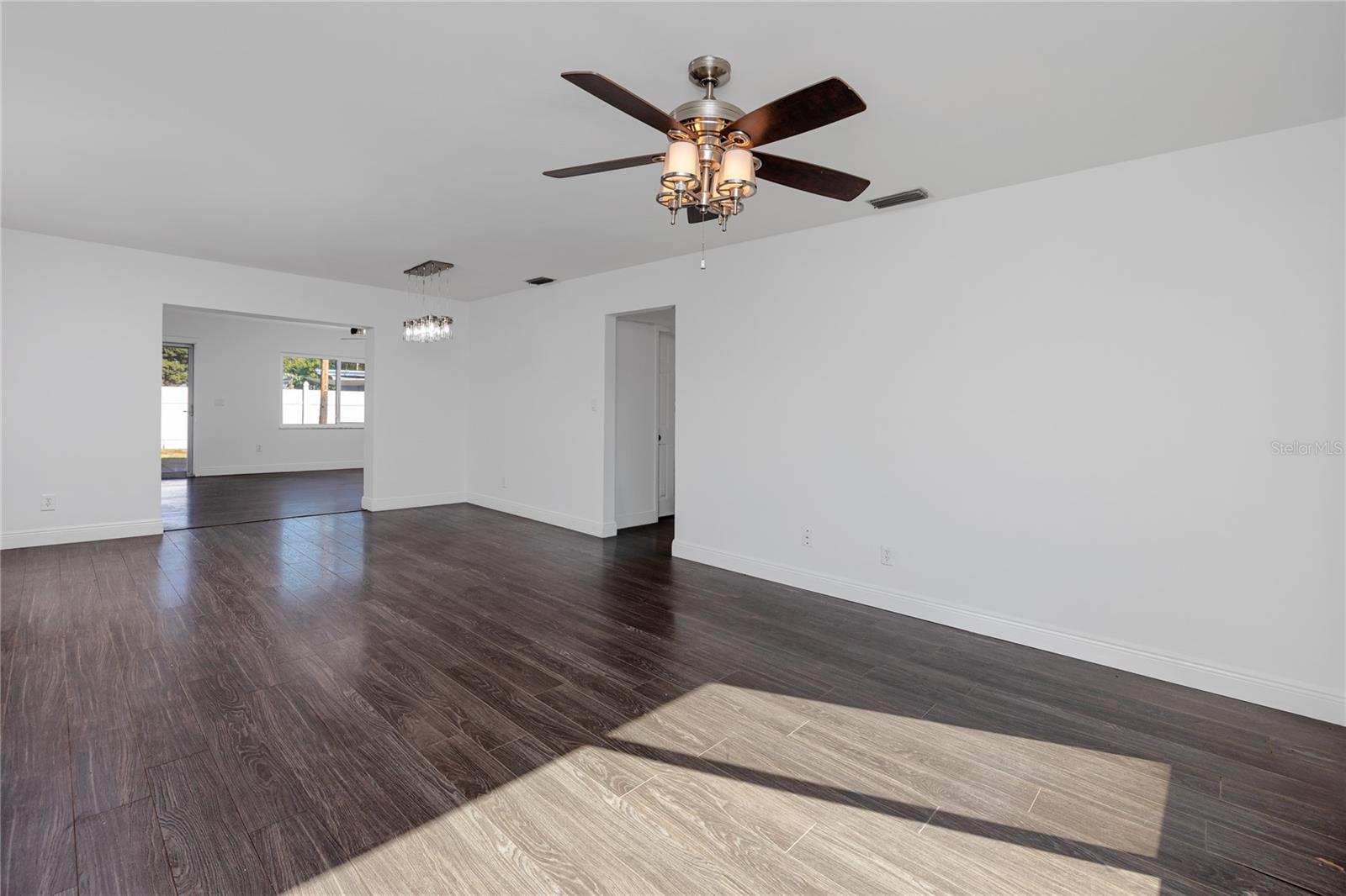 Large living/dining room combo with access to additional living space in the background.