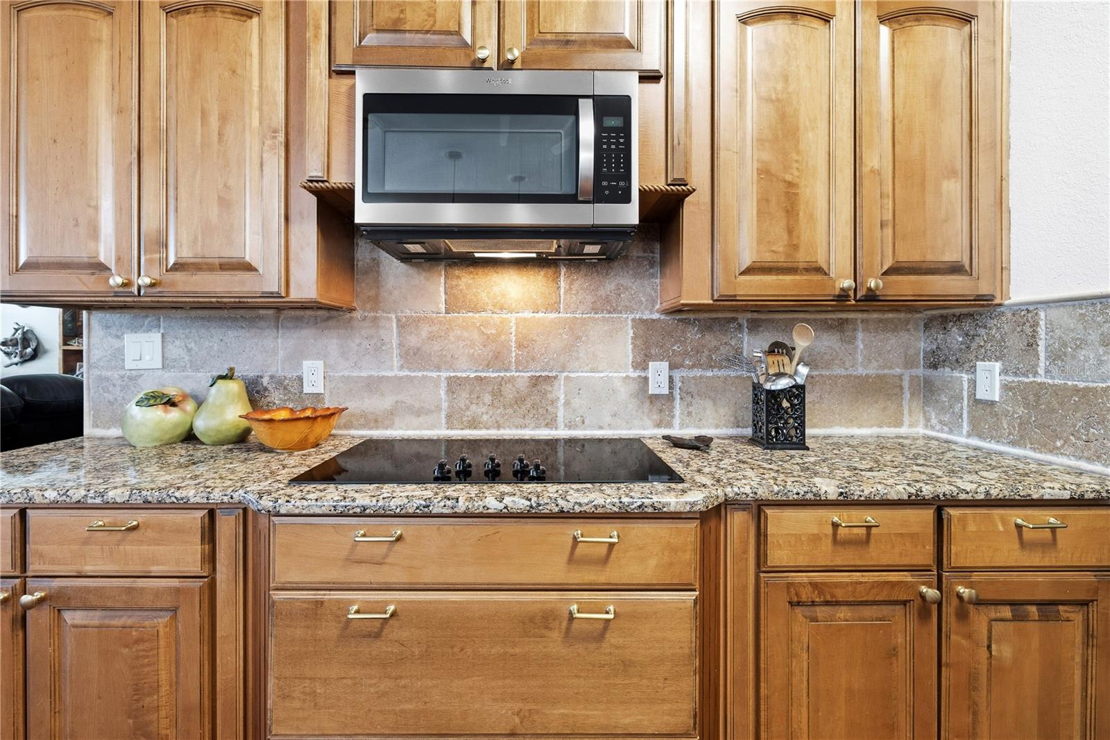 Newer cooktop and stone backsplash