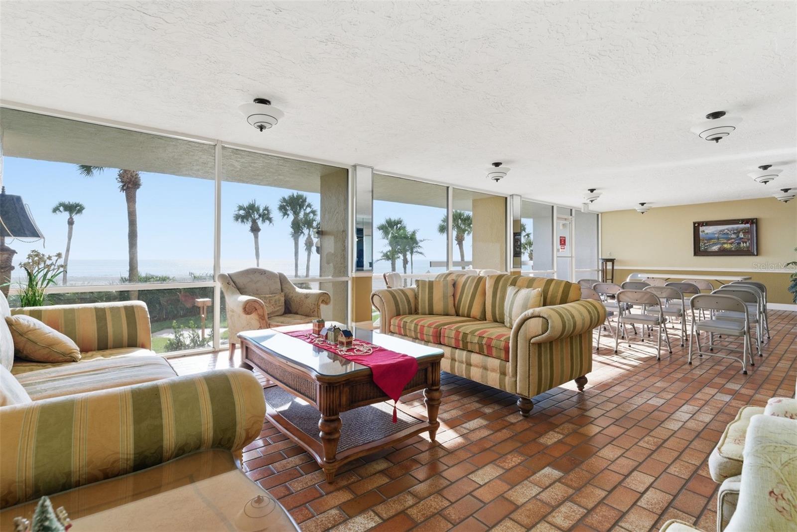 Beachfront lobby seating area where residents can unwind, socialize, and enjoy Gulf and palm tree views.