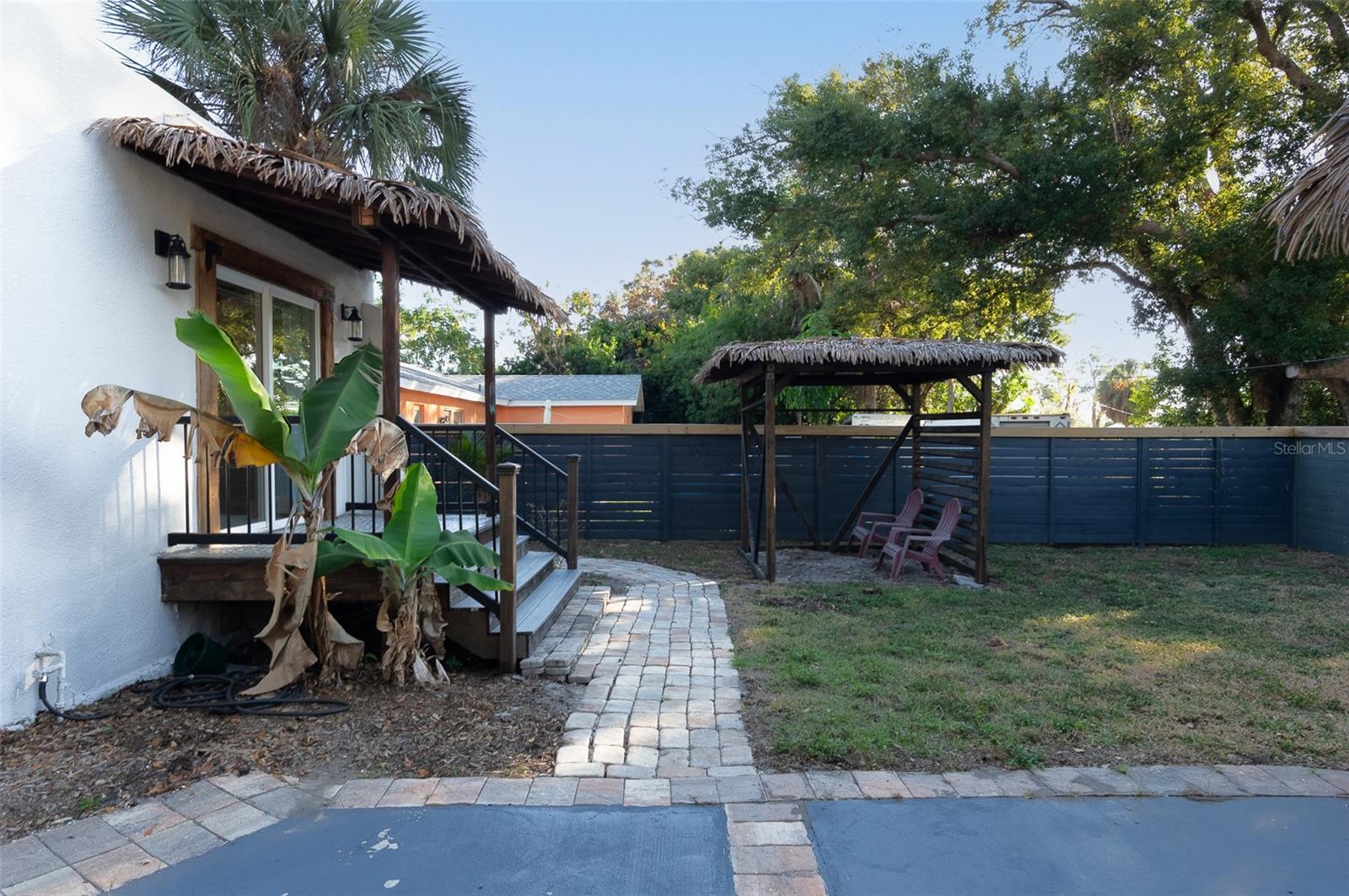 Private porch off primary bedroom with backyard and cabana seating area off private driveway