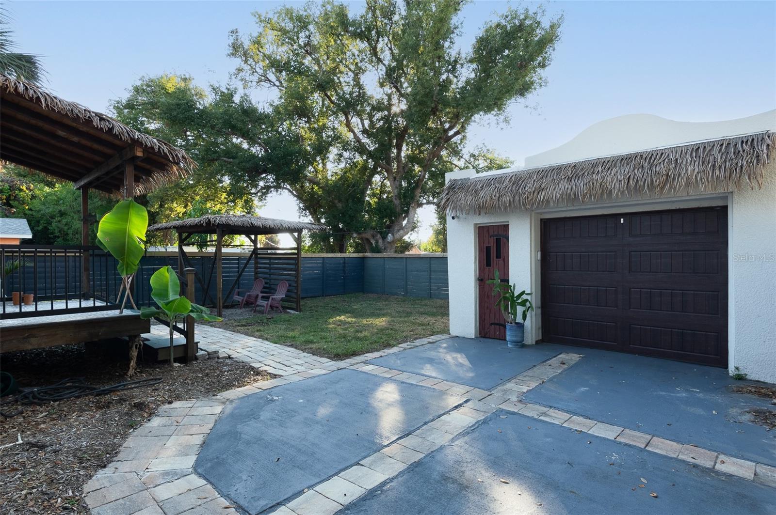 Detached 1 car garage accessible through private driveway gated with backyard, cabana seating area, and corner of the private porch off the primary bedroom.