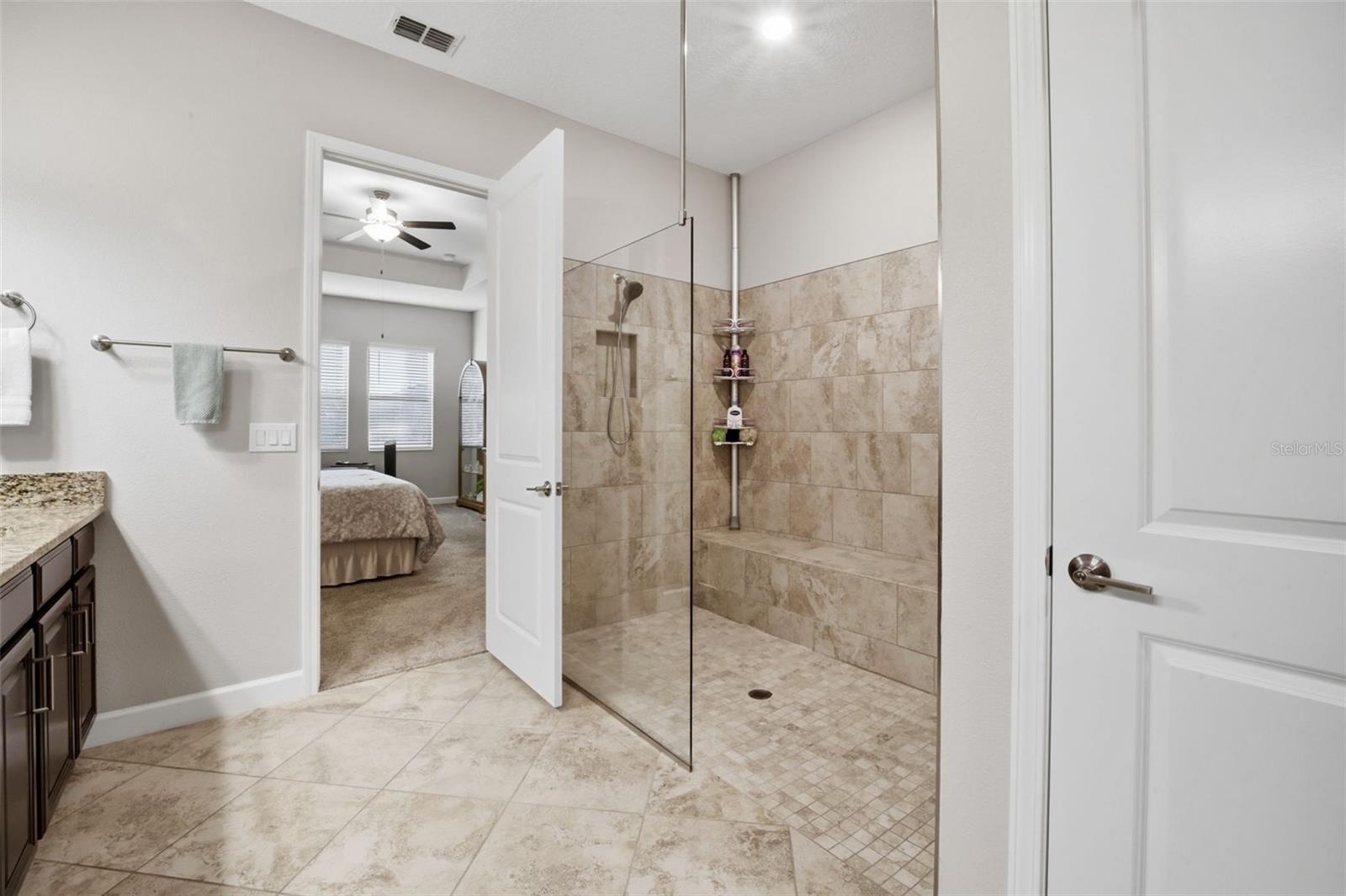 Spacious tiled shower boasts elongated seat