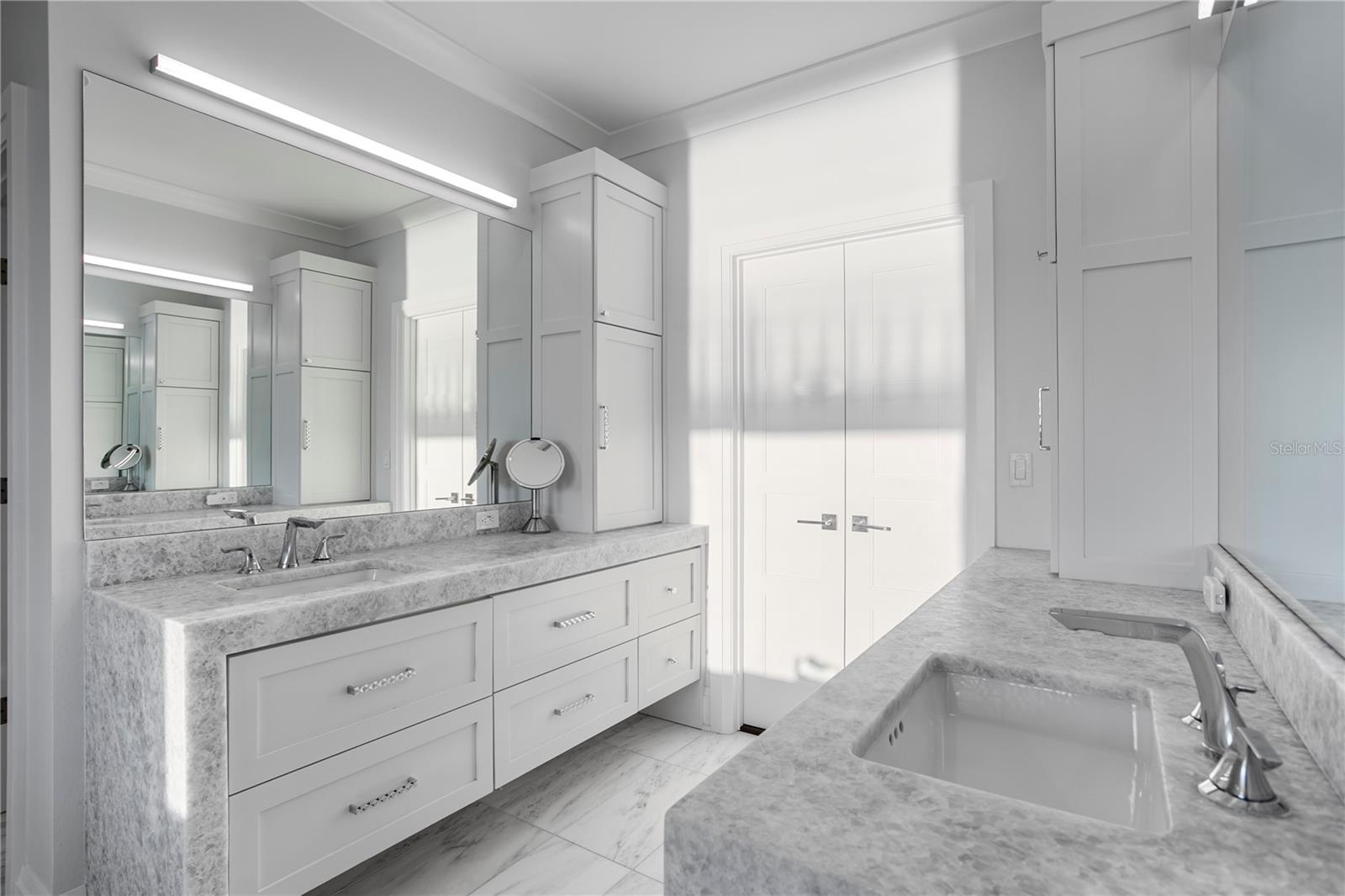 Primary bathroom features a double vanity with elegant waterfall edging