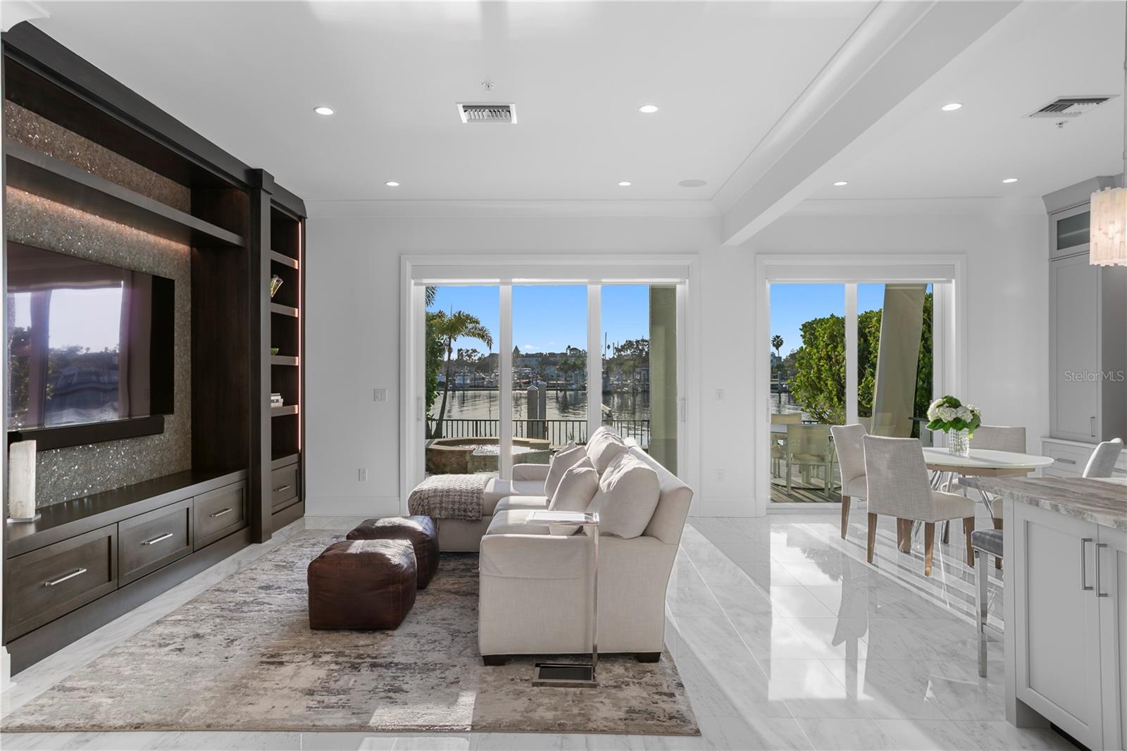 High impact doors and windows flood the space with natural light and frame views of the sparkling PebbleTec pool with Aqualink system, outdoor kitchen with gas grill and a private boat dock with lift and brand new seawall