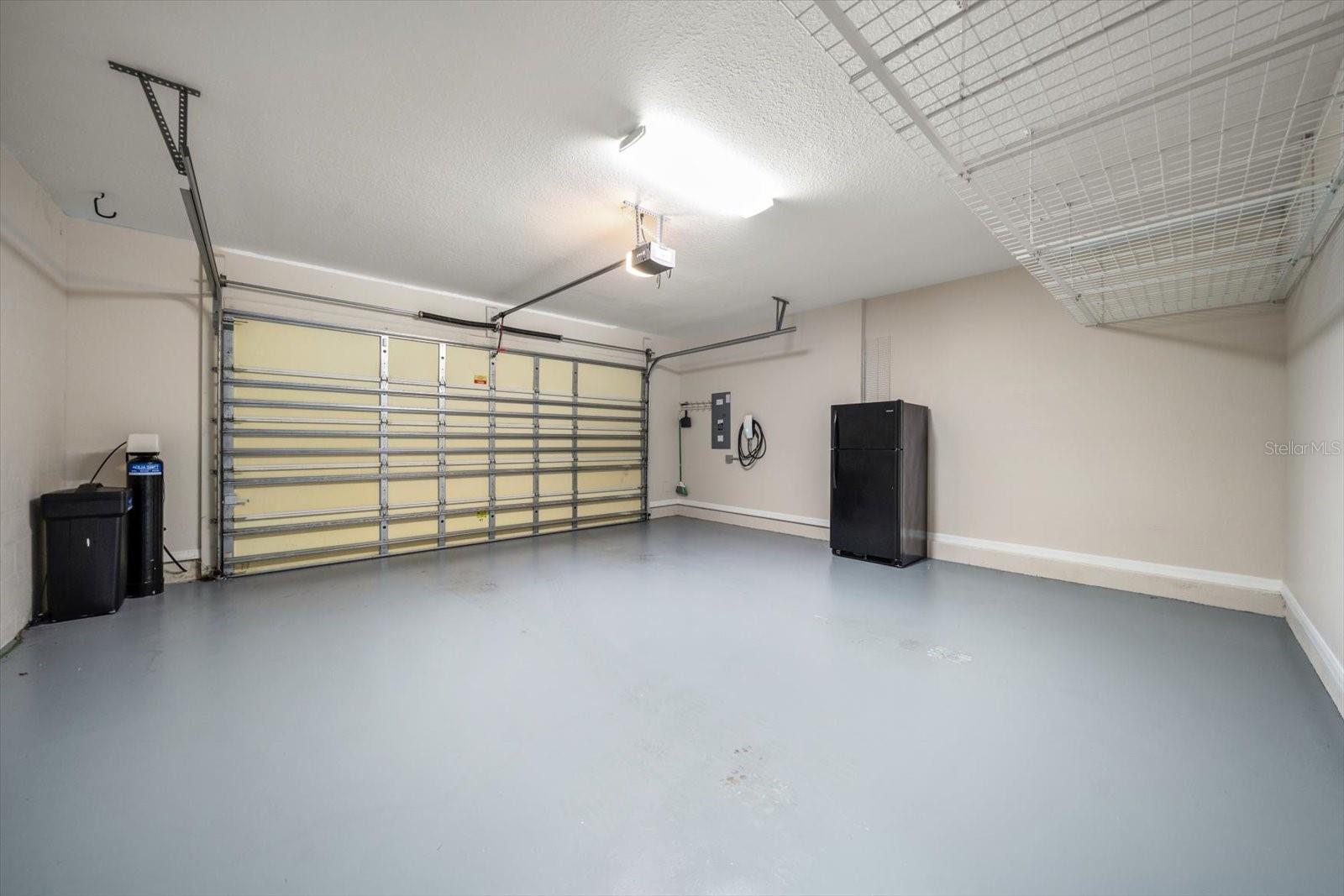 Painted garage floor with water softener and refrigerator