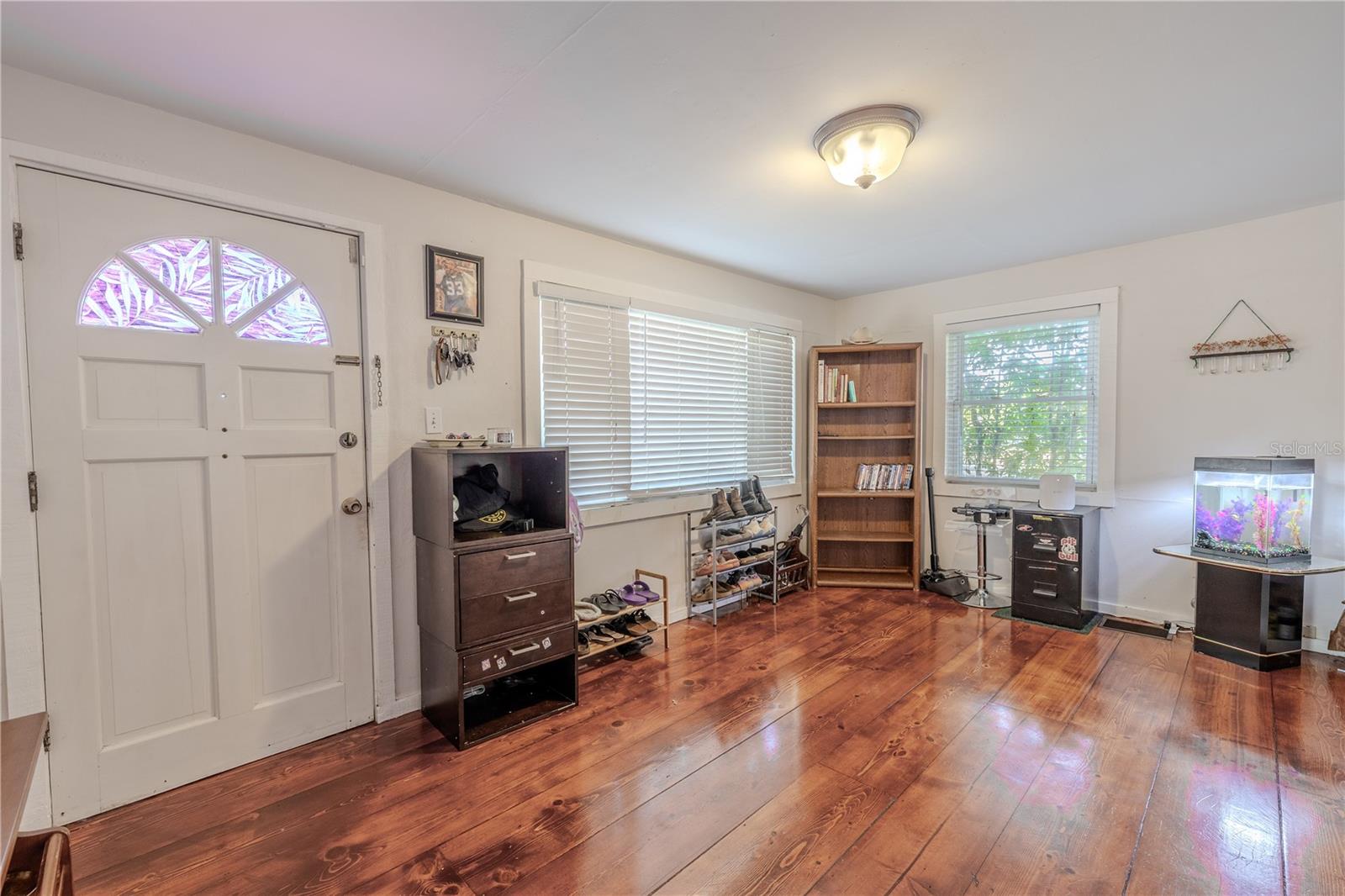 Step into a bright and welcoming foyer filled with natural light streaming through the large front and side windows. The solid four-panel front door, accented with a decorative window, adds charm and character to this historic 1918 home. Warm wood floors extend throughout the space, creating an inviting first impression the moment you walk in. This flexible entry area offers a comfortable transition into the rest of the home while highlighting the craftsmanship and warmth that define the property.