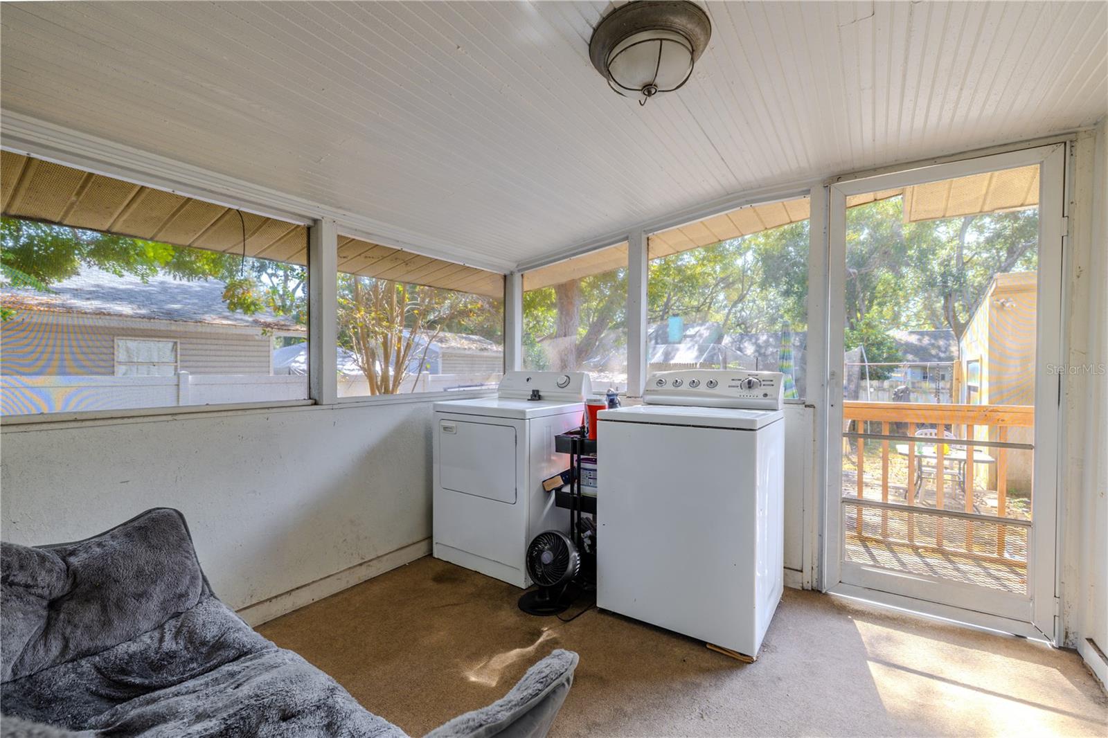 This screened-in porch, located just off the kitchen pantry, provides a bright and breezy space for household tasks. The washer and dryer are conveniently situated here, keeping laundry separate from the main living areas. Large screened windows allow plenty of natural light and airflow, while the exterior door offers easy access to the backyard deck. This versatile space adds practical functionality to the home.