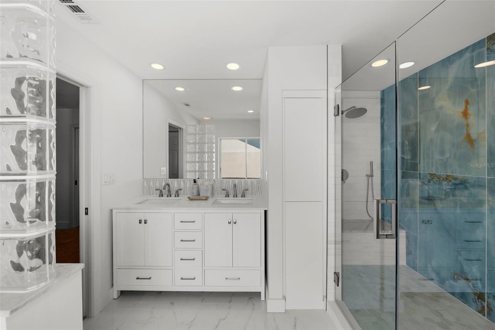 This redesigned bath features ample cabinetry, dual sinks, and custom linen storage.