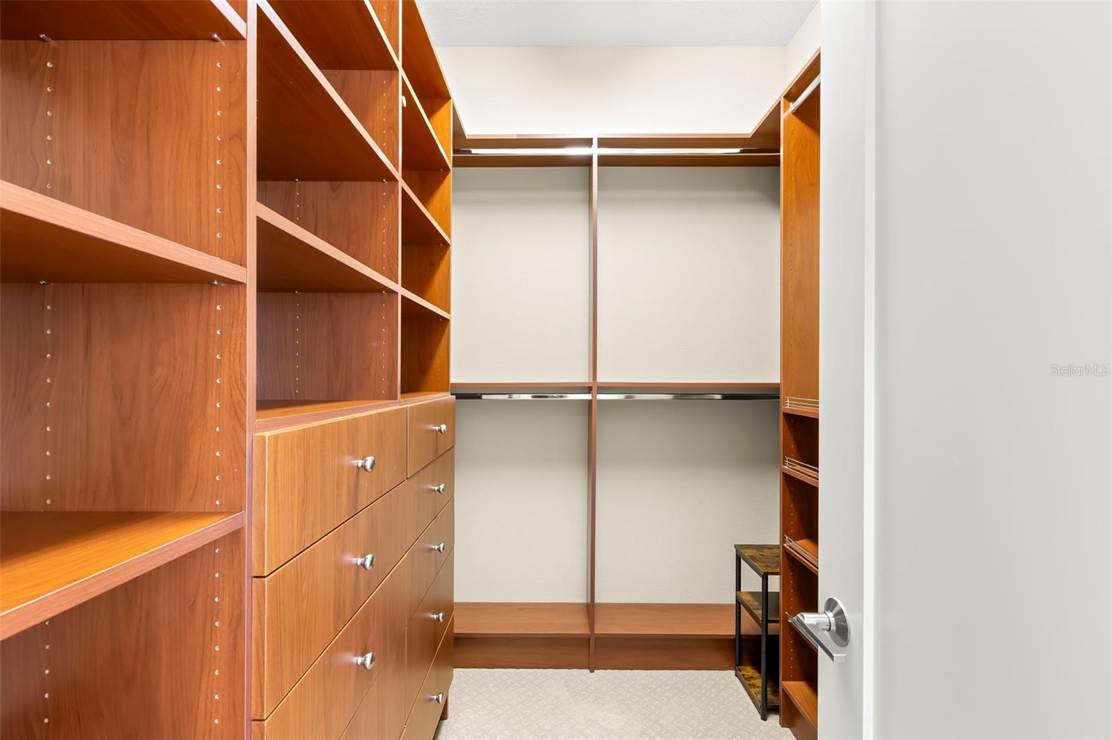 One of two walk-in closets in the Primary Suite including custom closet system, with drawers, shelves and shoe storage.