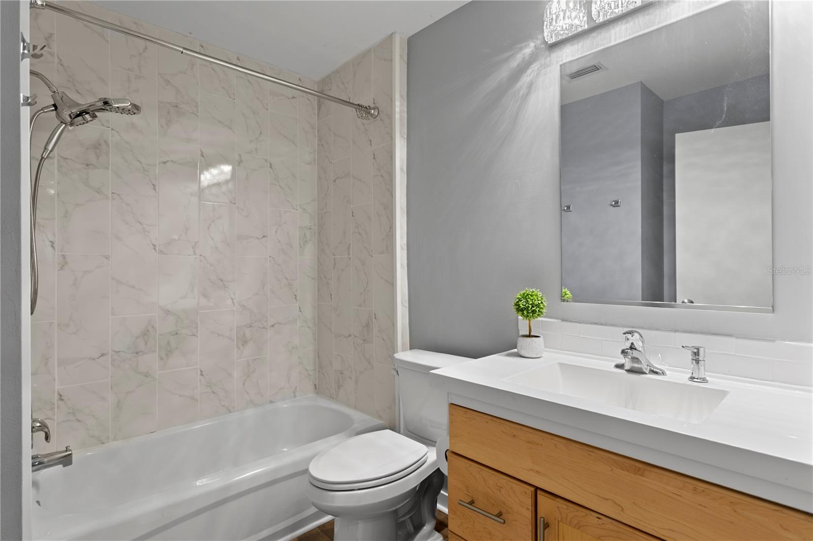 1st floor bath with newer bath tile, stone vanity and lighting