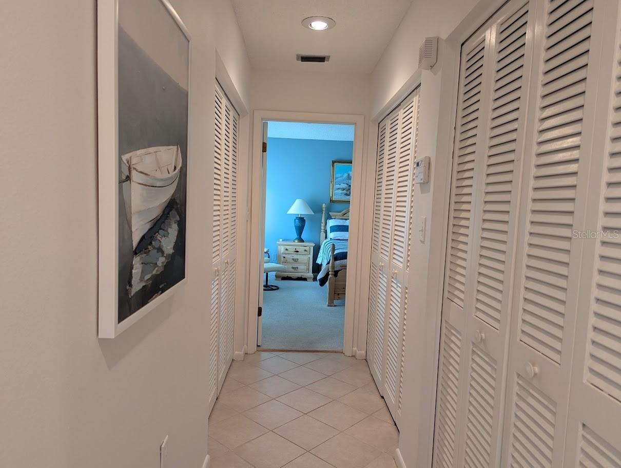 Hallway to primary suite with storage and laundry closet