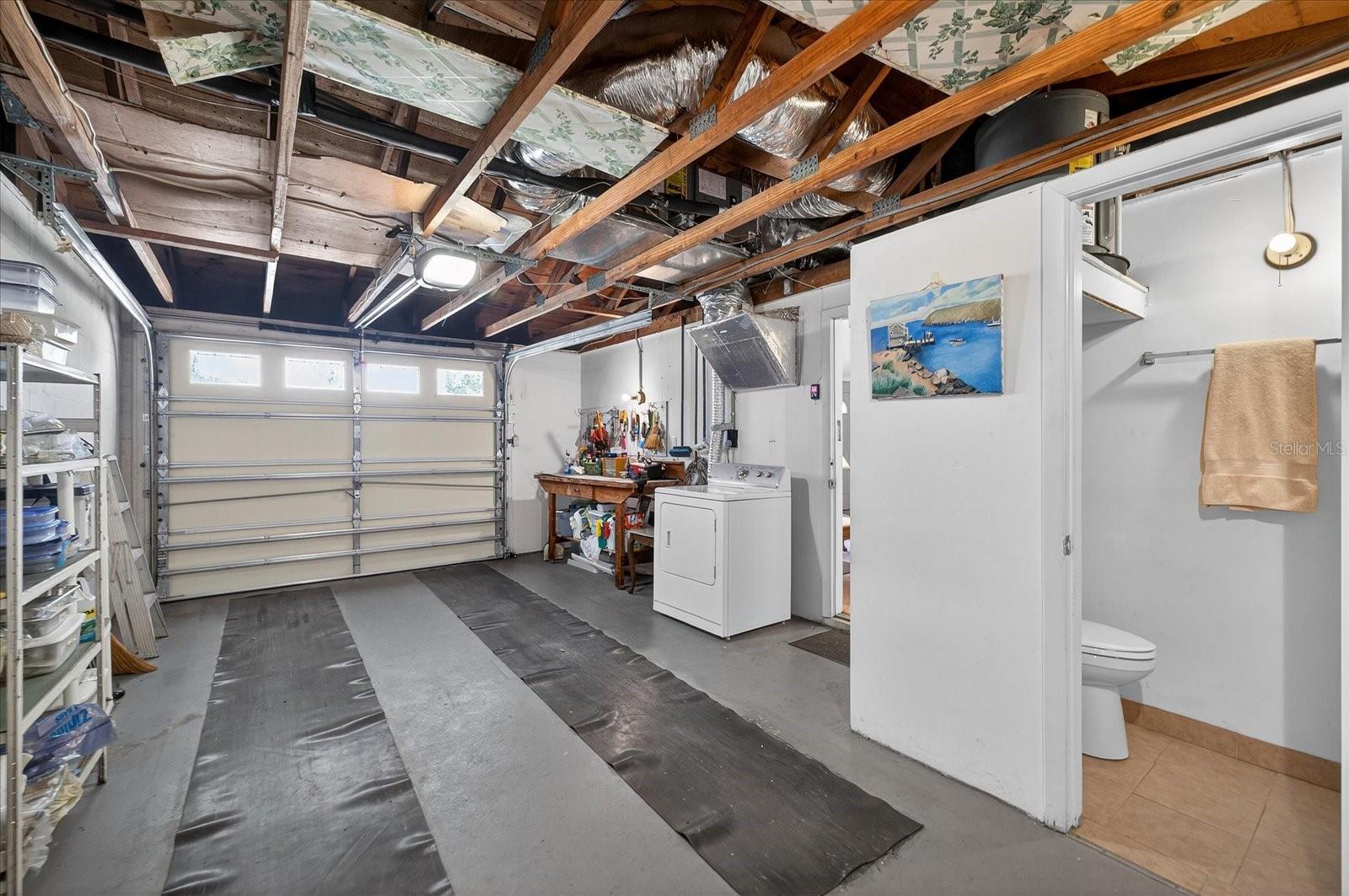 Garage view of workbench/dryer/bathroom