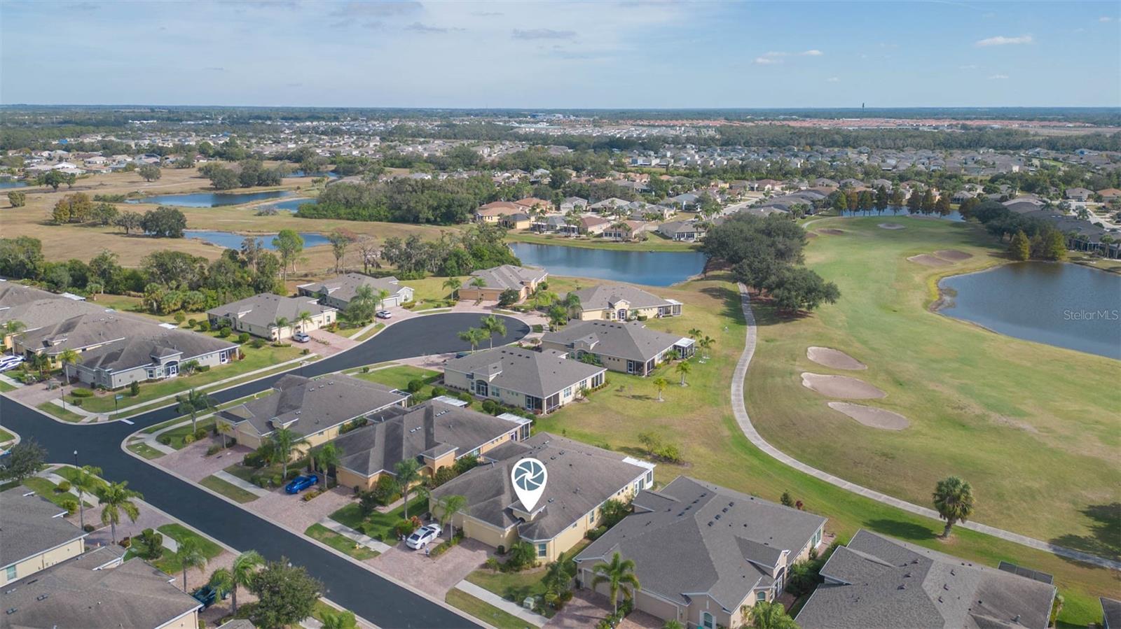 Home location from aerial view with golf course behind home.