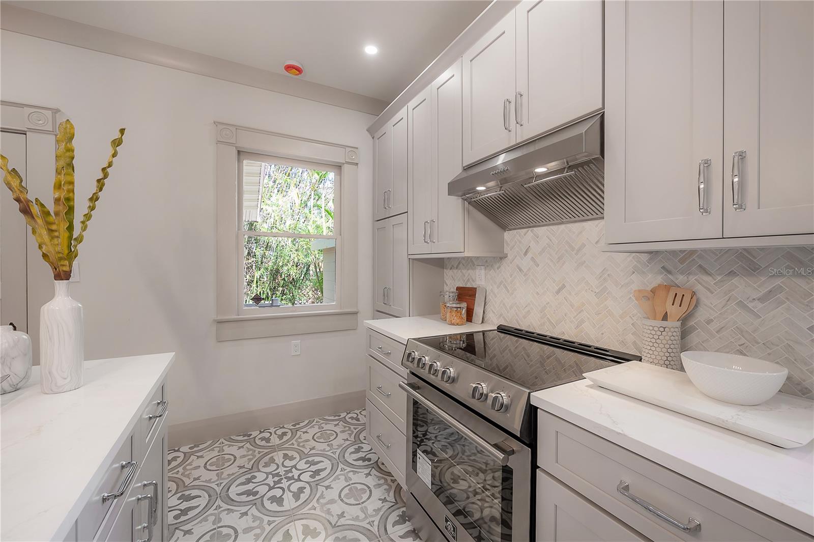 Light-filled kitchen with herringbone tile backsplash and large windows