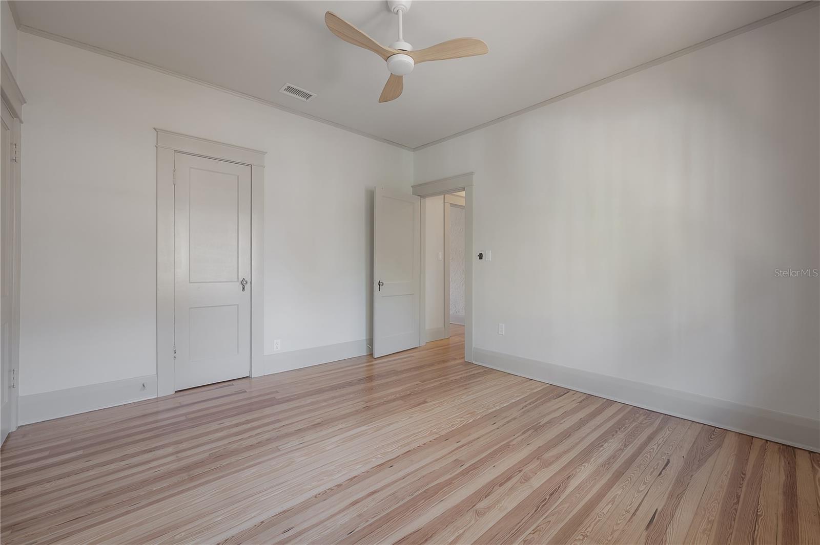 Crisp and inviting bedroom showcasing newly refinished floors