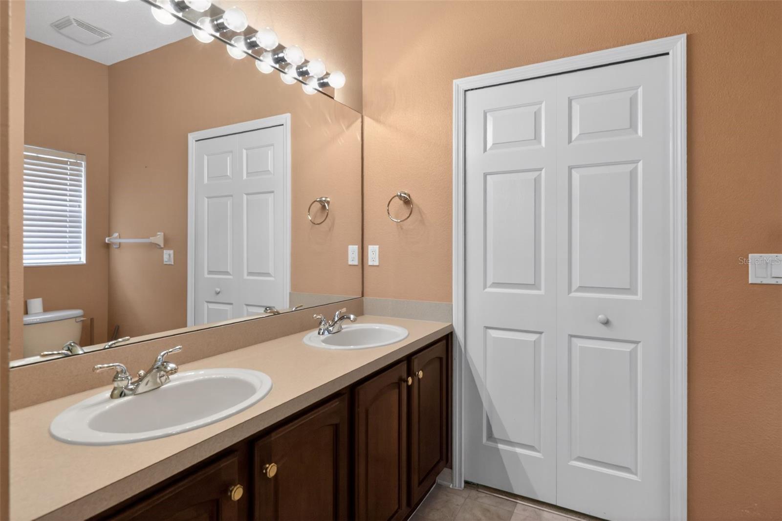 Double vanity in primary bathroom with large walk-in closet