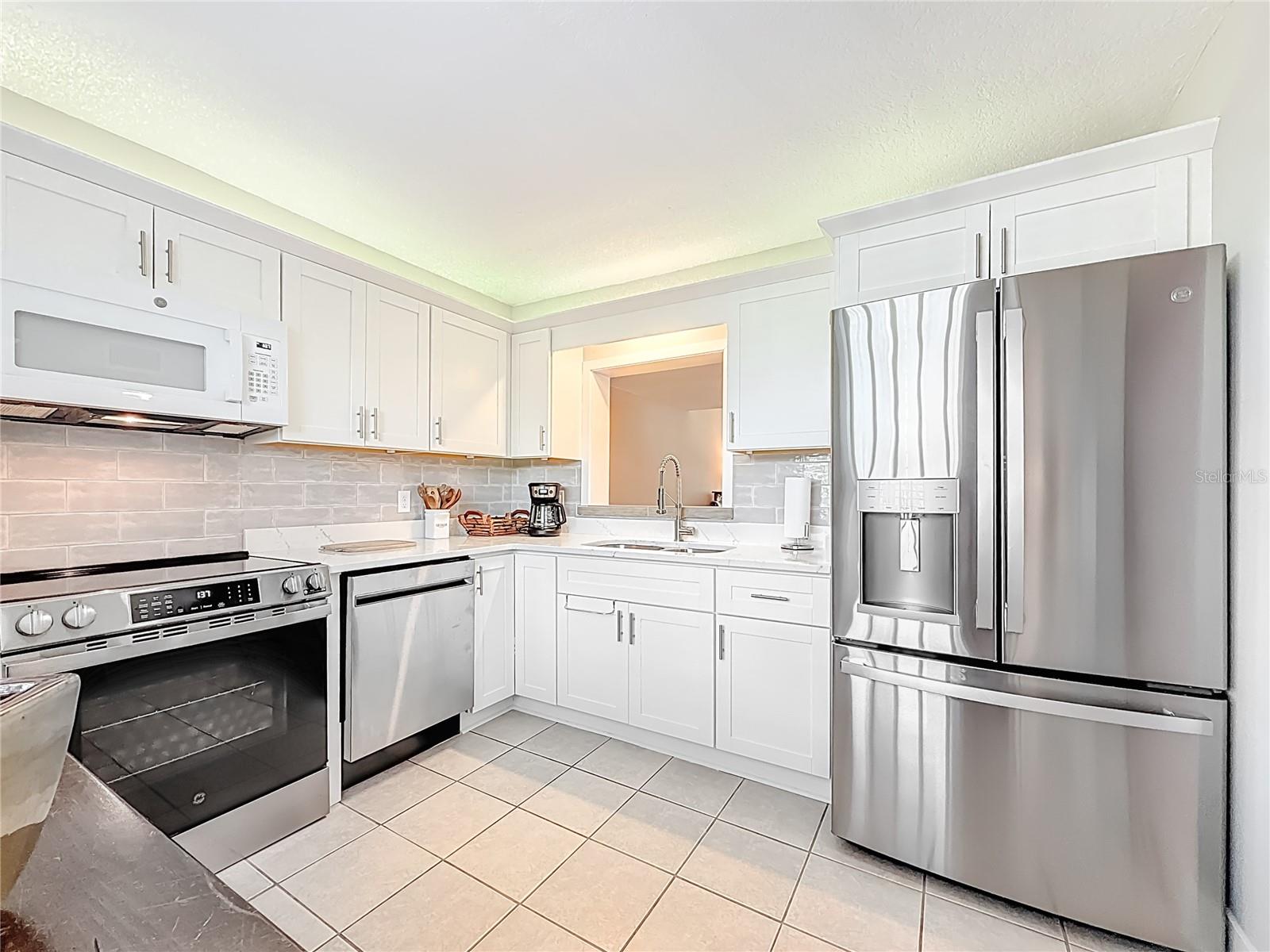 This beautiful updated kitchen features crisp new cabinetry, quartz countertops, modern backsplash & a full suite of stainless-steel appliances.
