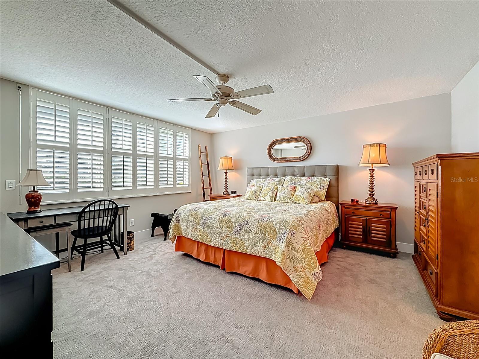 This is the spacious primary bedroom that offers plantation shutters and hurricane impact windows & overlooks the water.