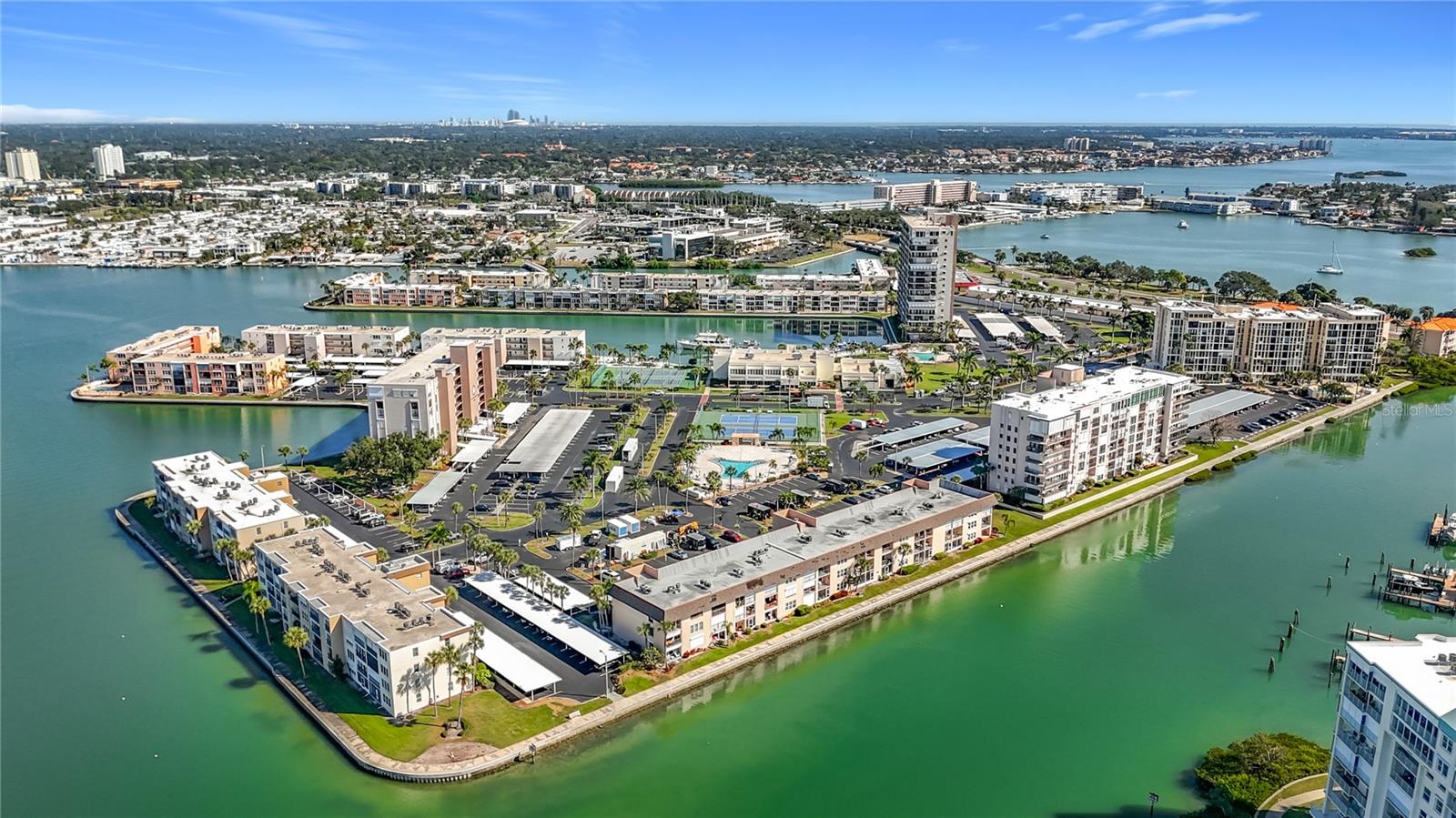 This aerial shows the entire gated Bay Island community that features 17 buildings and a clubhouse with a gym, entertainment room, card room, billiard room, meeting room, onsite management office, plus 6 heated pools, pickle ball courts and tennis courts, shuffleboard, a marina, grilling areas and a 1.5 mile walkway.