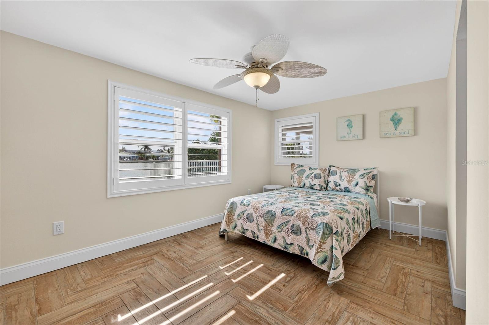 Guest bedroom with herringbone wood-look tile, plantation shutters and an en-suite bathroom