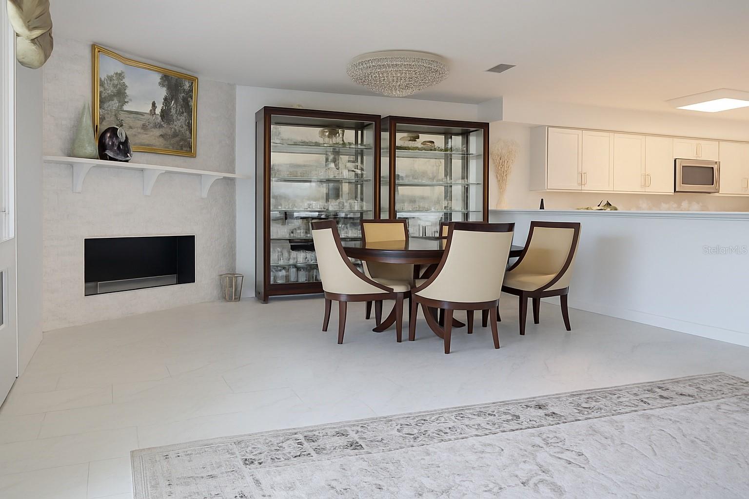 Bright, modern dining area with elegant fireplace, glass cabinets, and seamless flow into the updated kitchen.