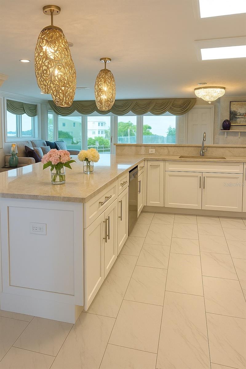 Bright open kitchen with elegant lighting, marble countertops, and expansive windows offering beautiful waterfront views.