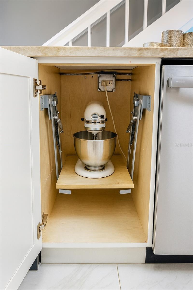 Hidden cabinet lift stores a KitchenAid mixer neatly, providing convenient access while keeping countertops clutter-free.