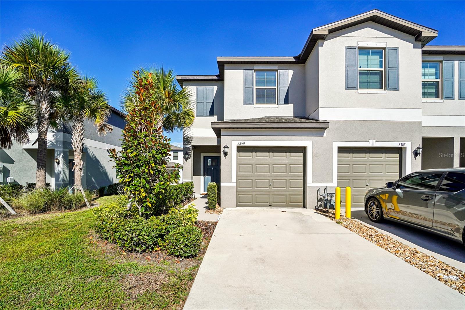 Front Exterior – Welcoming townhome exterior featuring a clean, well-maintained façade with modern paint tones, a single-car garage, and a neatly landscaped front walkway framed by mature palms and shrubs.
