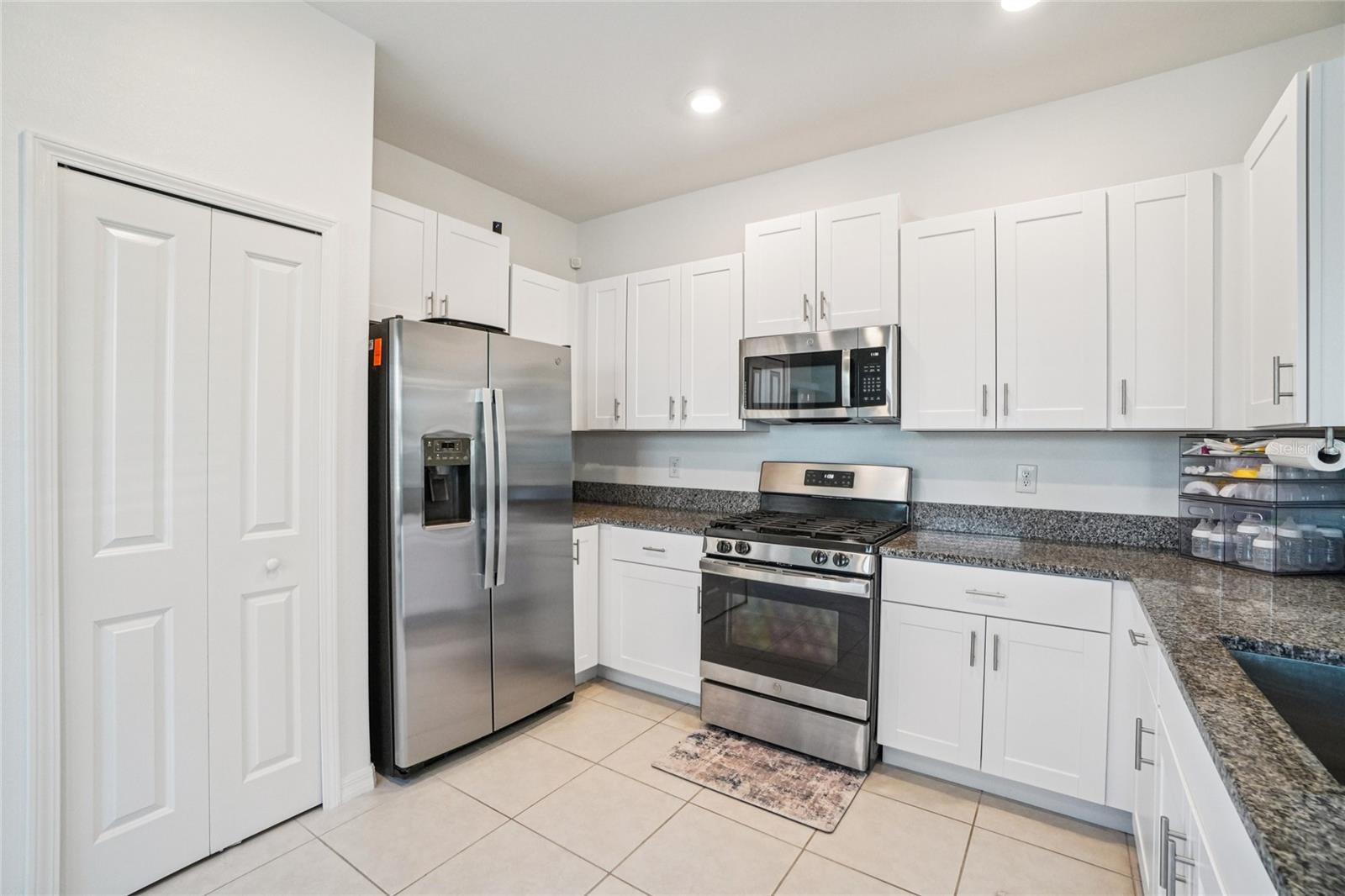 Kitchen – Angle 1 – Modern kitchen equipped with stainless steel appliances, white shaker cabinetry, and ample granite counter space, offering both style and functionality.