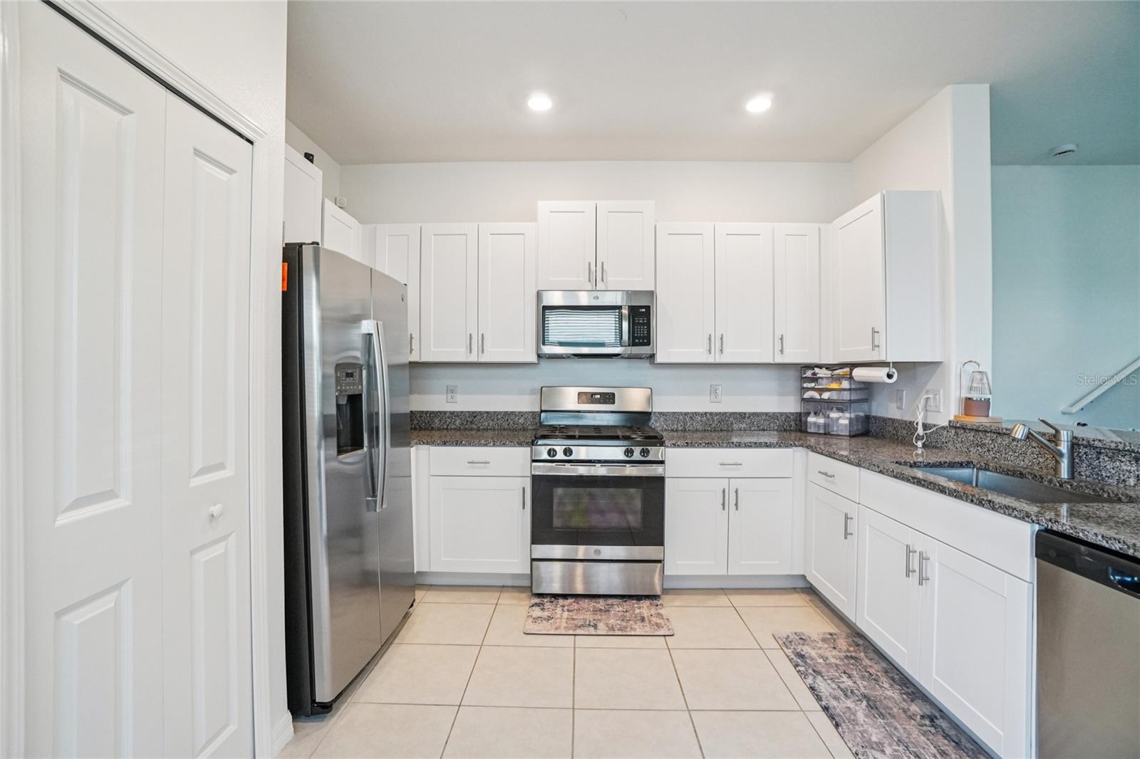 Kitchen – Angle 2 – A wider view of the kitchen showcasing abundant upper and lower cabinets, a gas range, and a spacious layout ideal for meal prep.
