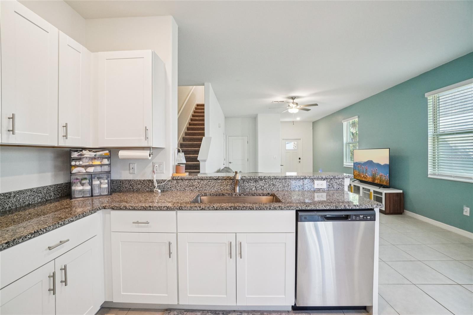 Kitchen – Sink & Bar View – Granite countertops extend to a raised bar seating area, connecting the kitchen to the main living space for an open, social layout.