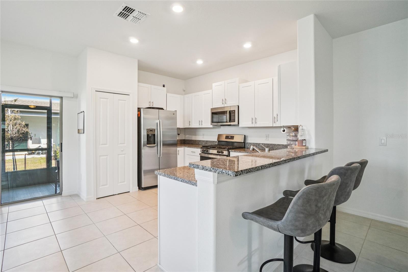 Kitchen – Angle Toward Patio – The kitchen overlooks the dining area and patio access, highlighting the natural light and easy movement between spaces.
