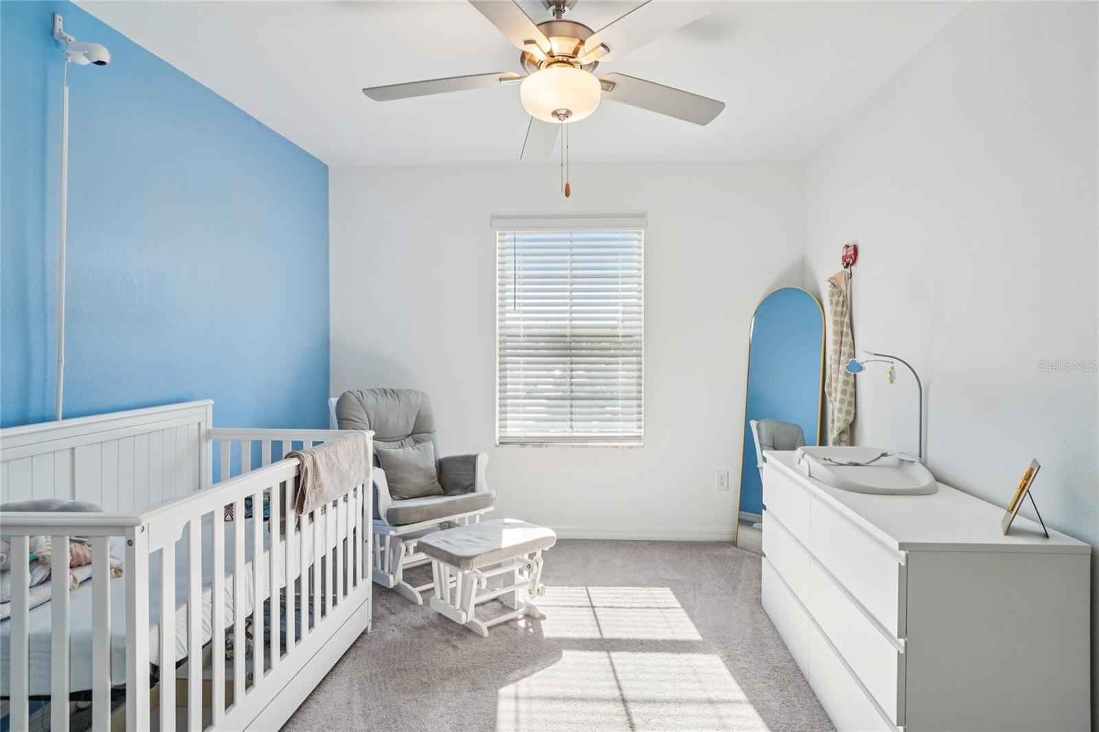 Bedroom 2 – Angle 1 – Spacious secondary bedroom featuring soft carpet, a ceiling fan, and a large window offering natural light.