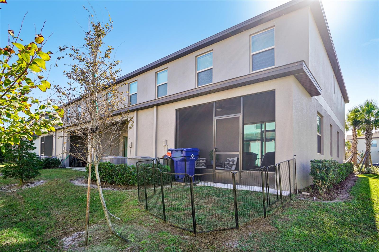 Rear Exterior – Angle 3 – Wider backyard perspective highlighting the screened patio and newly planted trees.