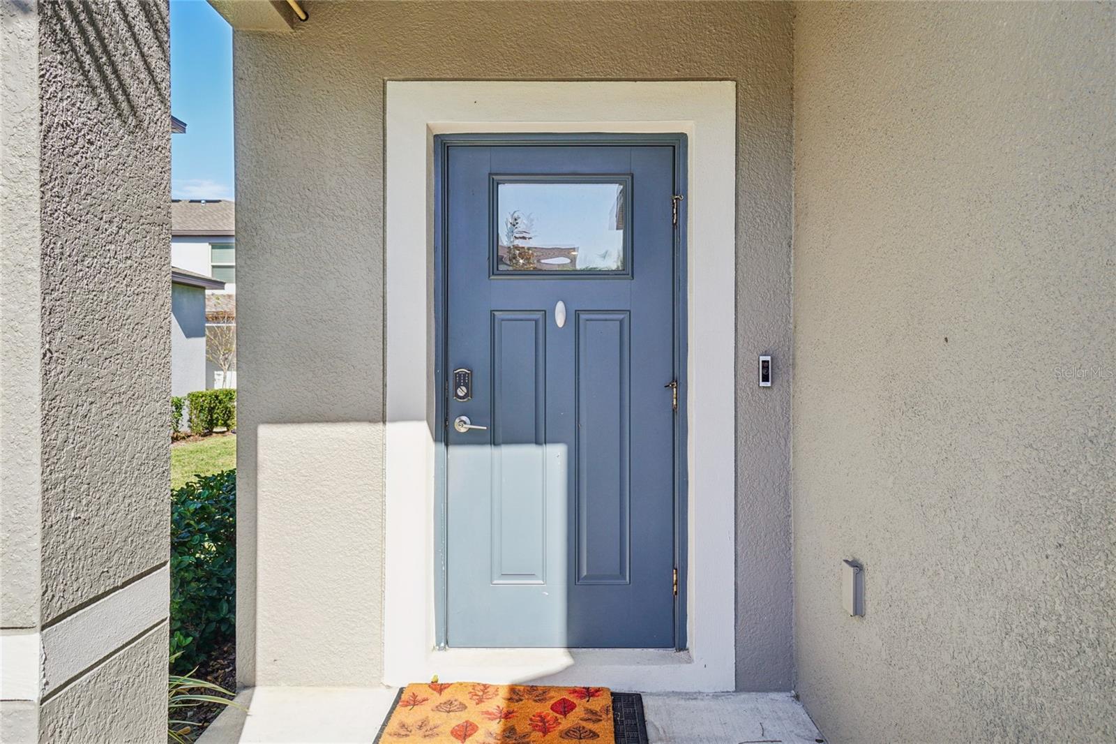 Front Door – The covered entry features a paneled front door with a transom window and keyless smart lock, offering both style and convenience.