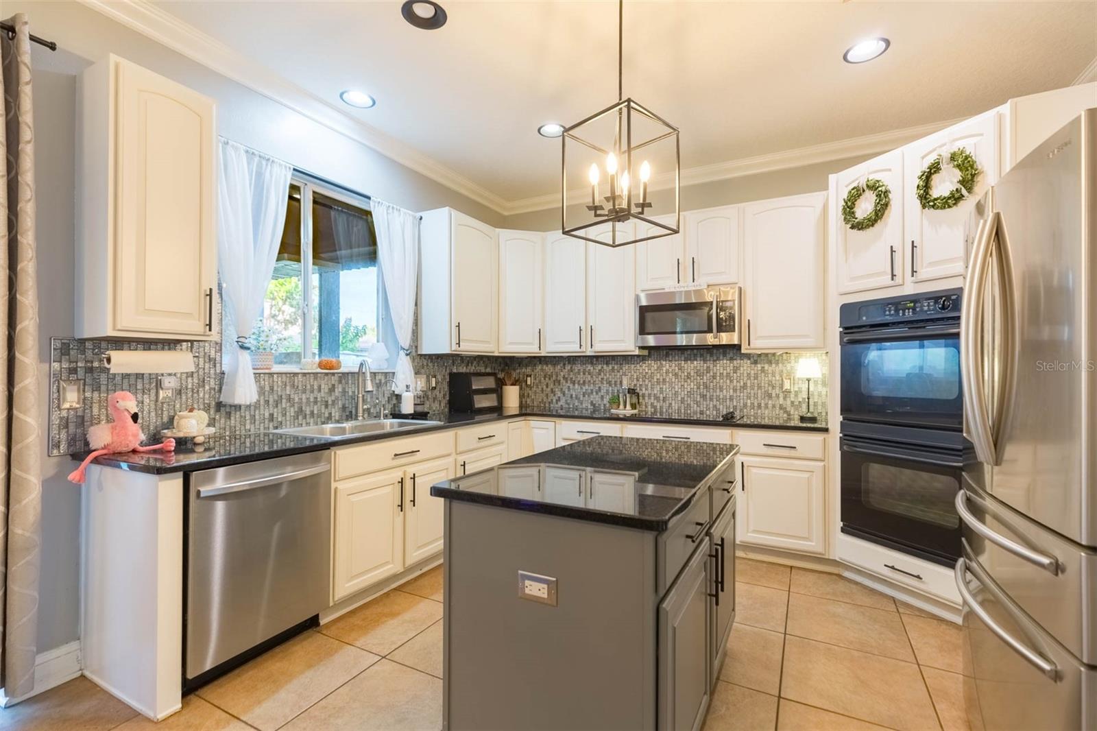 Open kitchen including contrasting cabinetry, four door refrigerator, double ovens and designer backsplash