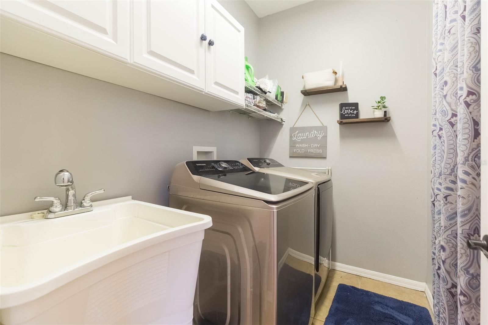 Newer washer and dryer with double sink and additional storage above