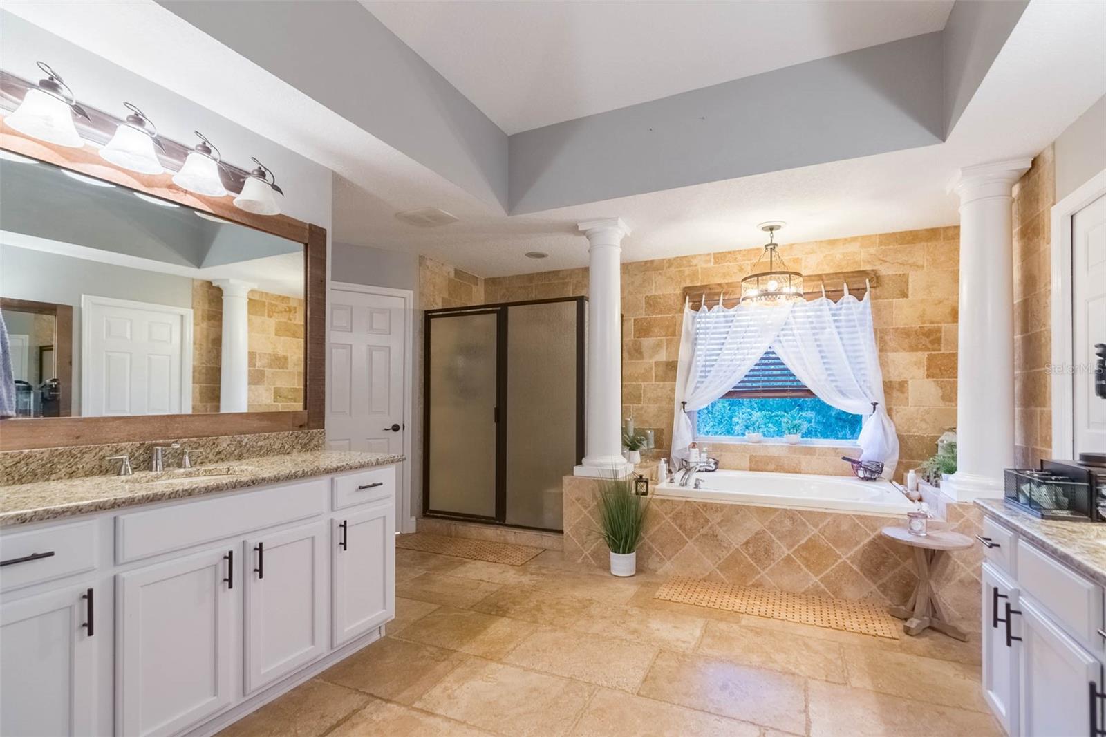 Primary bath with two long granite countertops, large shower, soaking tub and his and hers closets