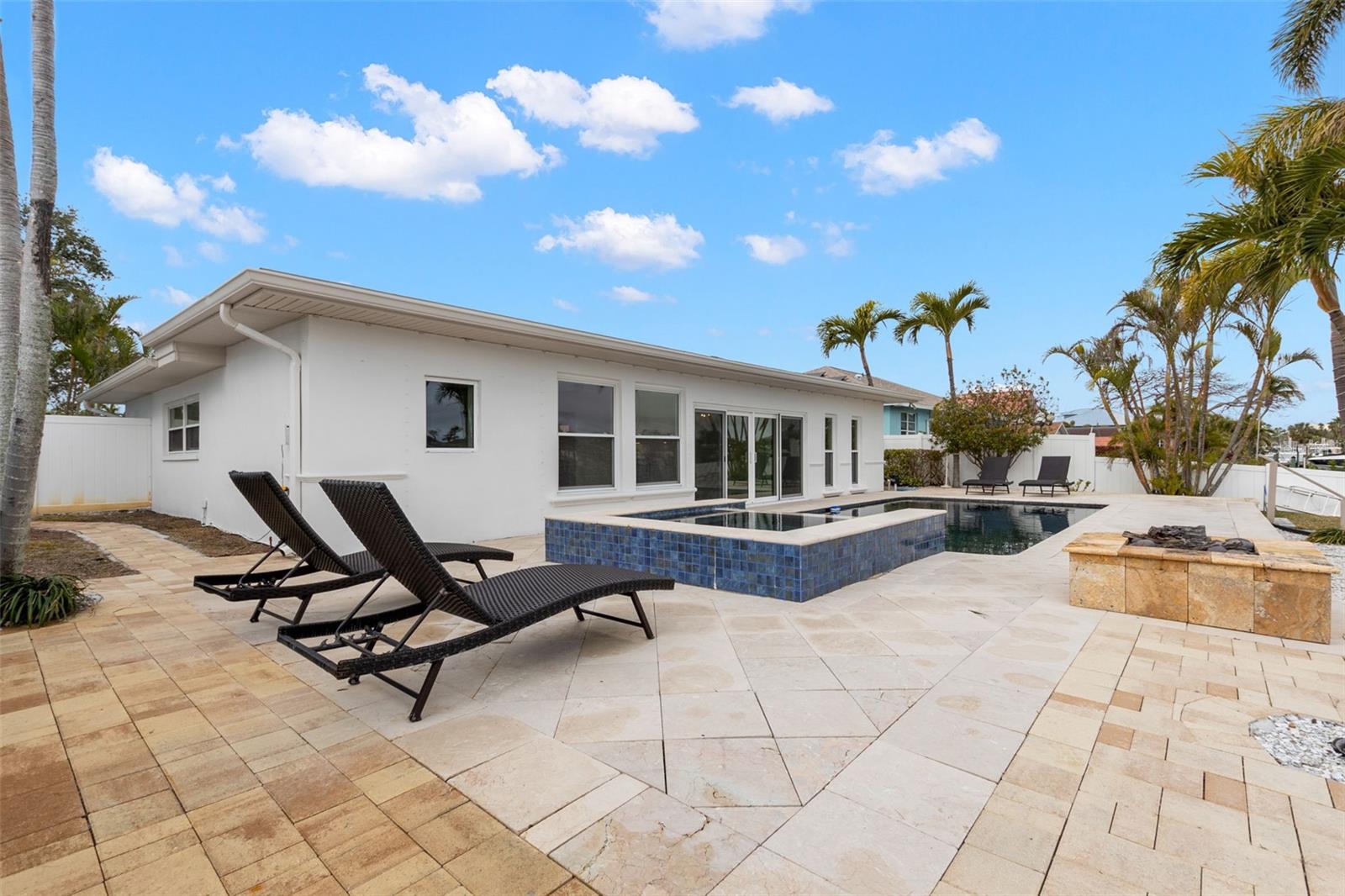 Spacious travertine patio featuring a heated spa and generous lounging space.