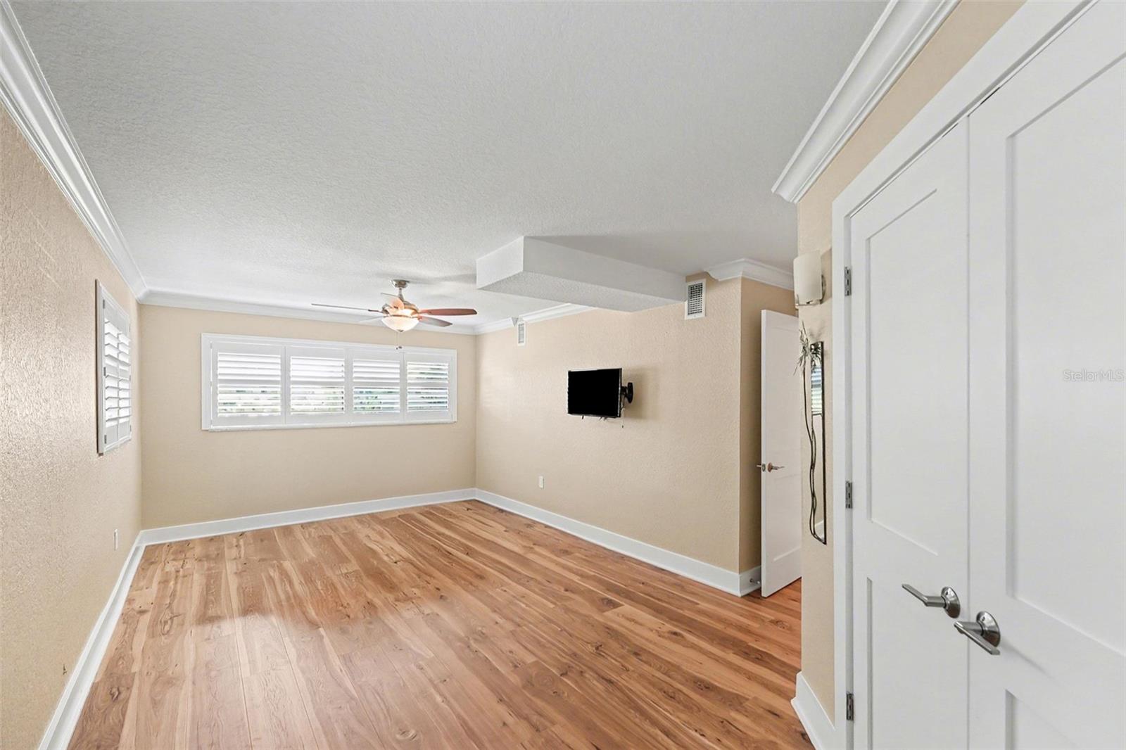 Primary Bedroom is the perfect size for enjoying your own coastal sanctuary. Large closet with plenty of space, Plantation shutters, ceiling fan, mounted TV, new flooring, 4" baseboards and crown molding.