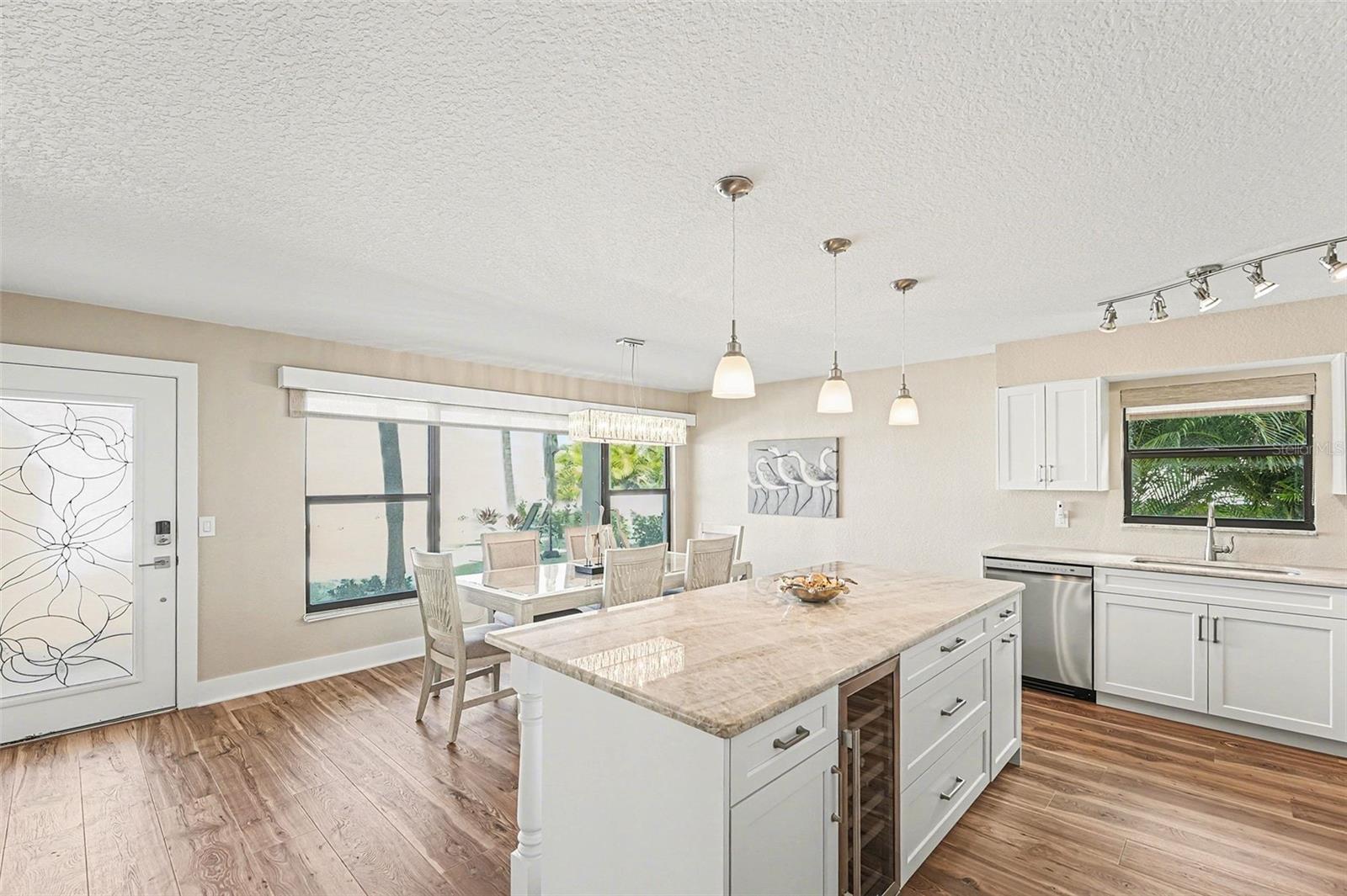 Quartzite counters, oversized kitchen island and space for a large dining room, new cabinets, appliances, 4" baseboards, paint, and flooring. Enjoy remote window shades with expansive views of the beach from both the living room and kitchen.  Bonus kitchen window allows for Florida breezes too!