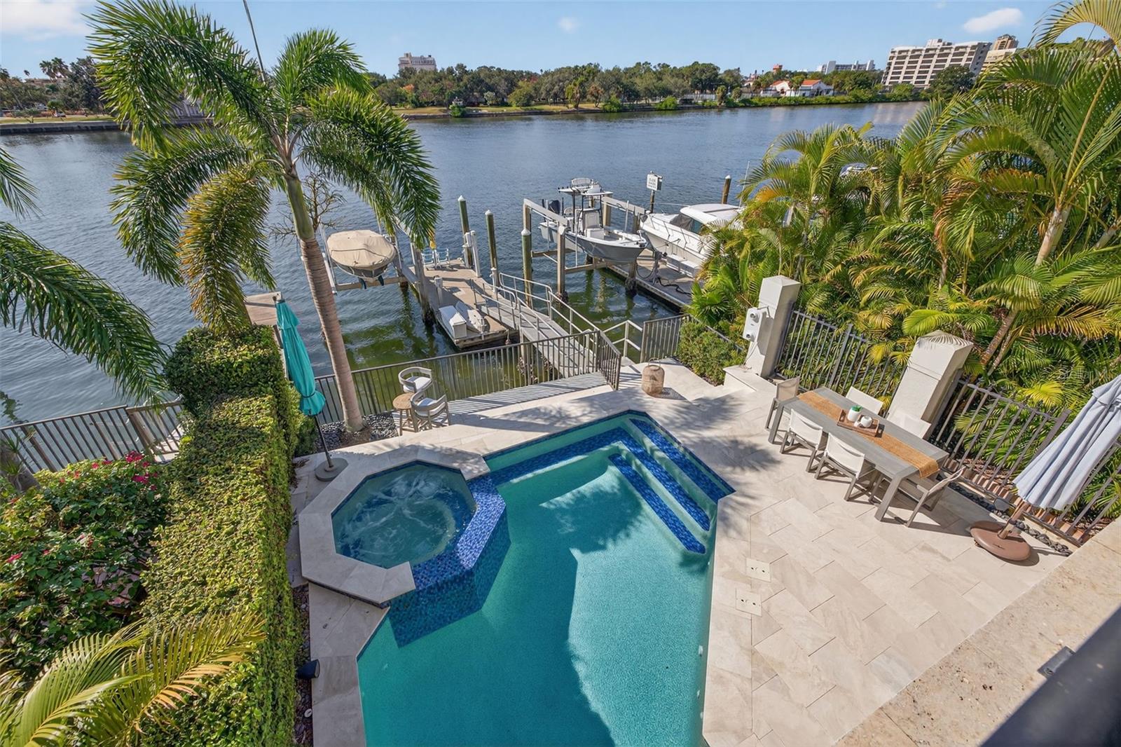 A serene private balcony offering panoramic views of the pool, water, and deep-water dock.