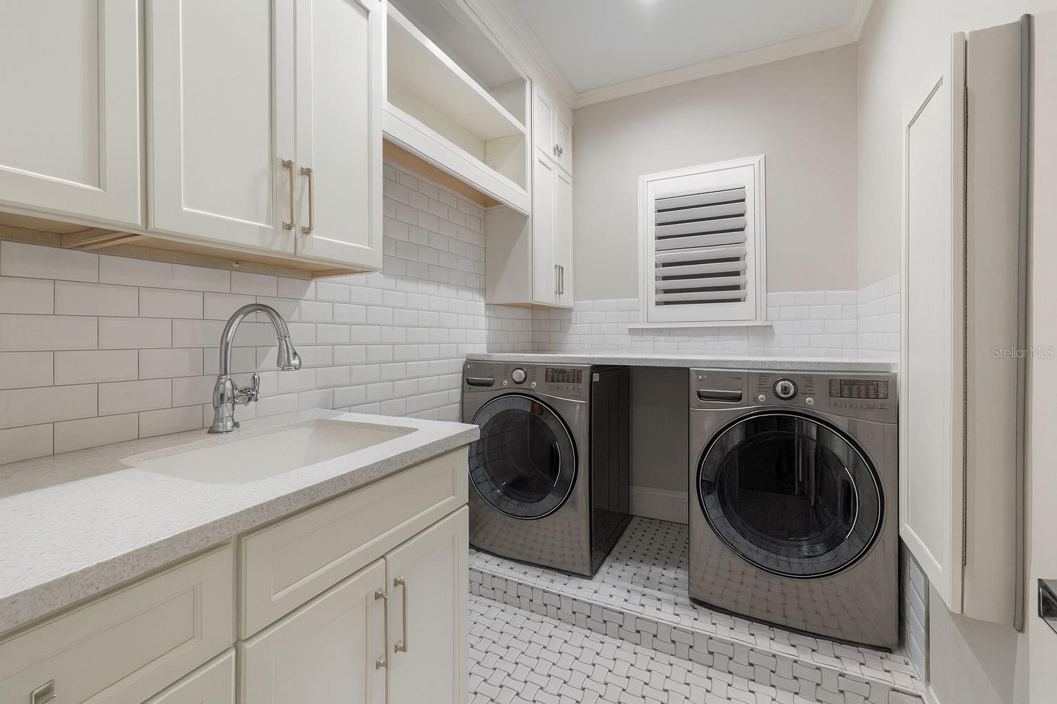 Well-appointed laundry room featuring a Corian sink and abundant storage.