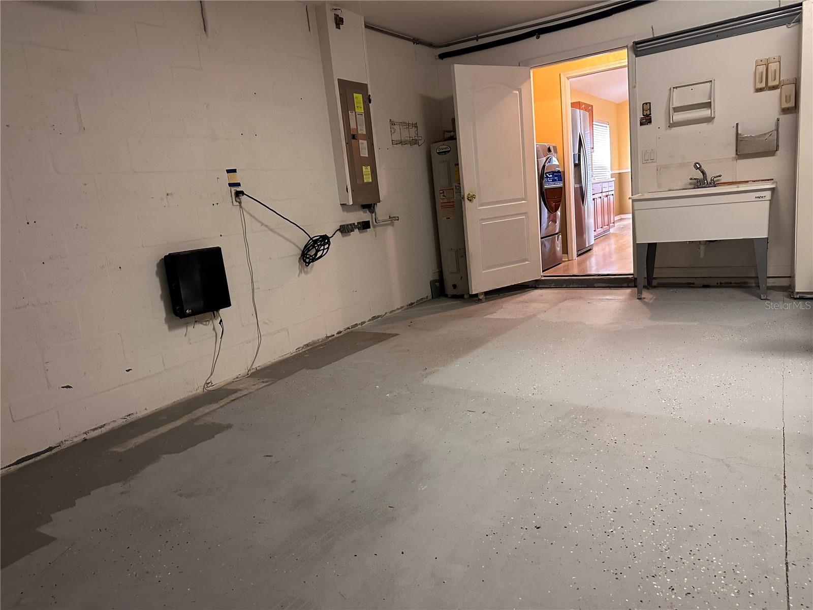 2 car garage with owned water softer, workbench, cabinet and screen slider doors in front of garage metal door.