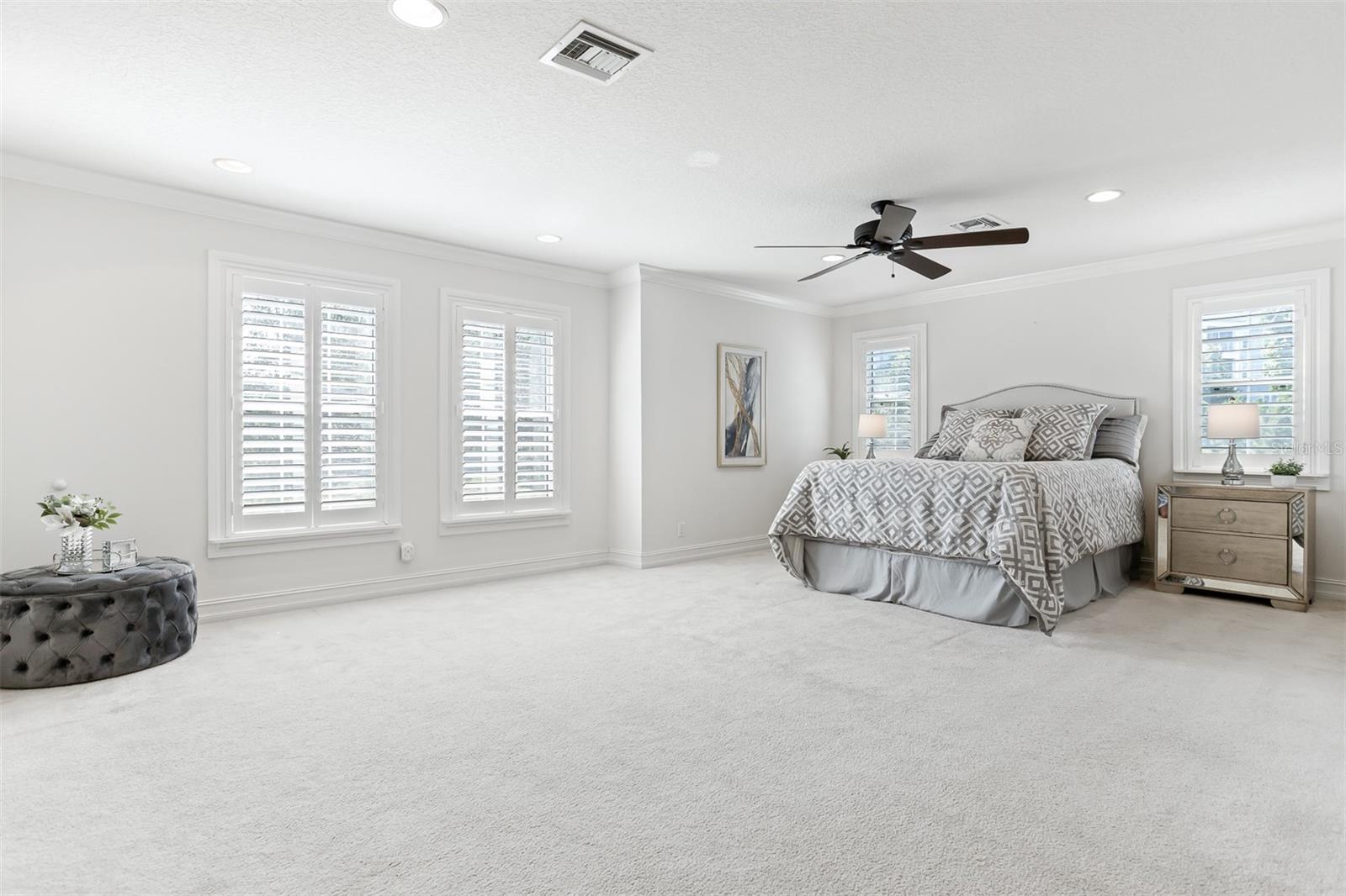 Large primary suite boasting natural light with custom shutters, generous walk-in closets and offering luxury and comfort.