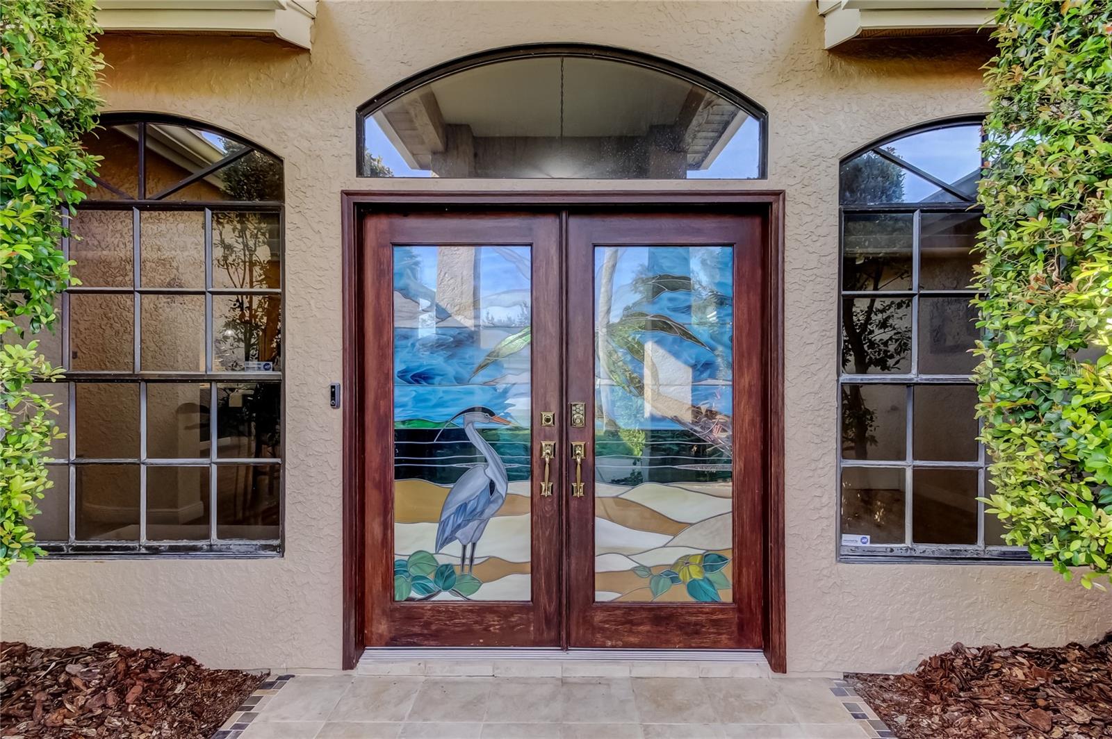 Featuring a custom double front door, a largeintegrated stained glass panel with a coastal beach theme