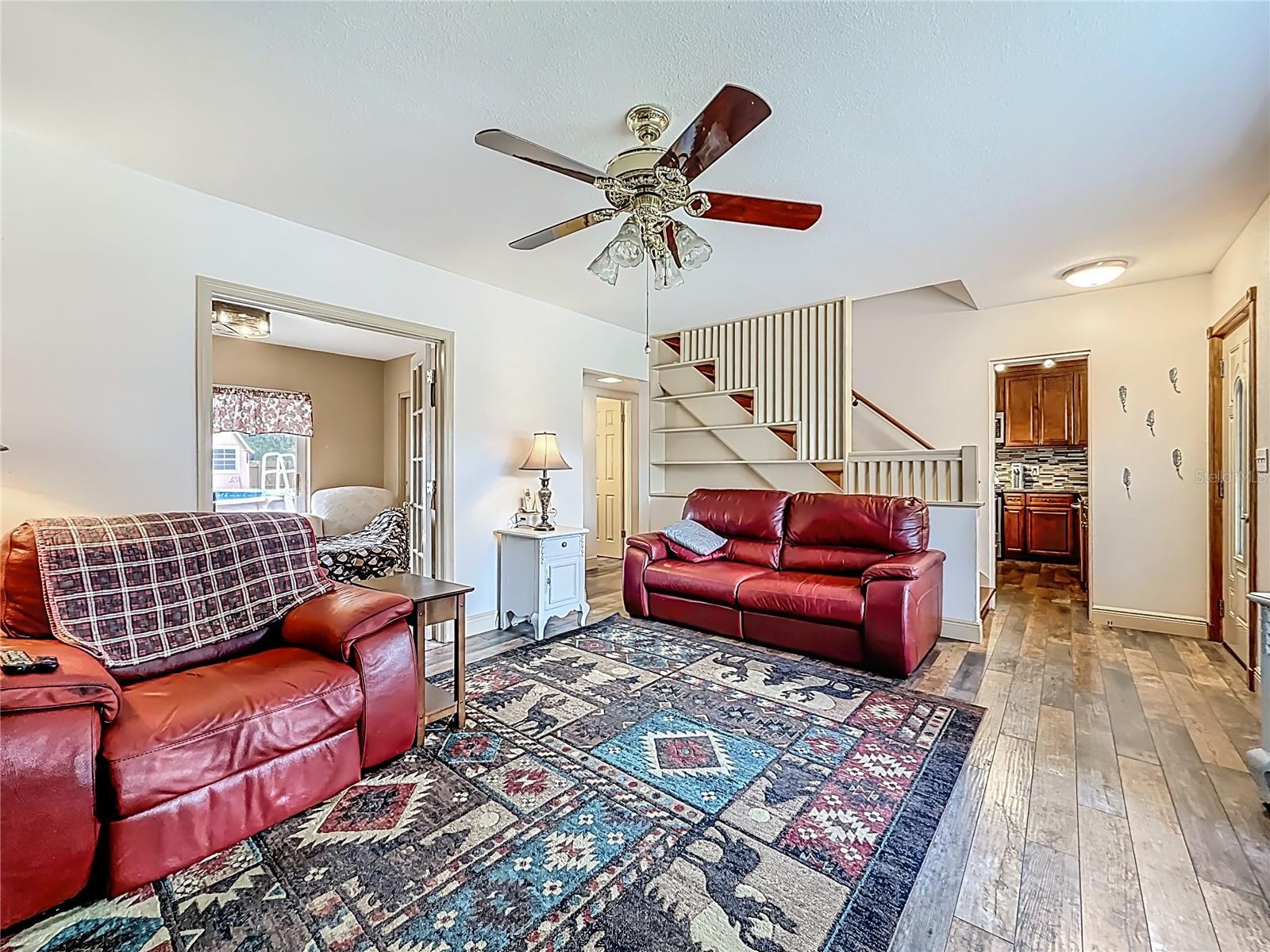 Behind you is the fireplace & hearth, view into the living room. From here, you may notice the opening on the right leading into the kitchen. Behind the couch are some shelves. Yes, the banister is also Red Cherry Oak. Bothe were updated in 2019.