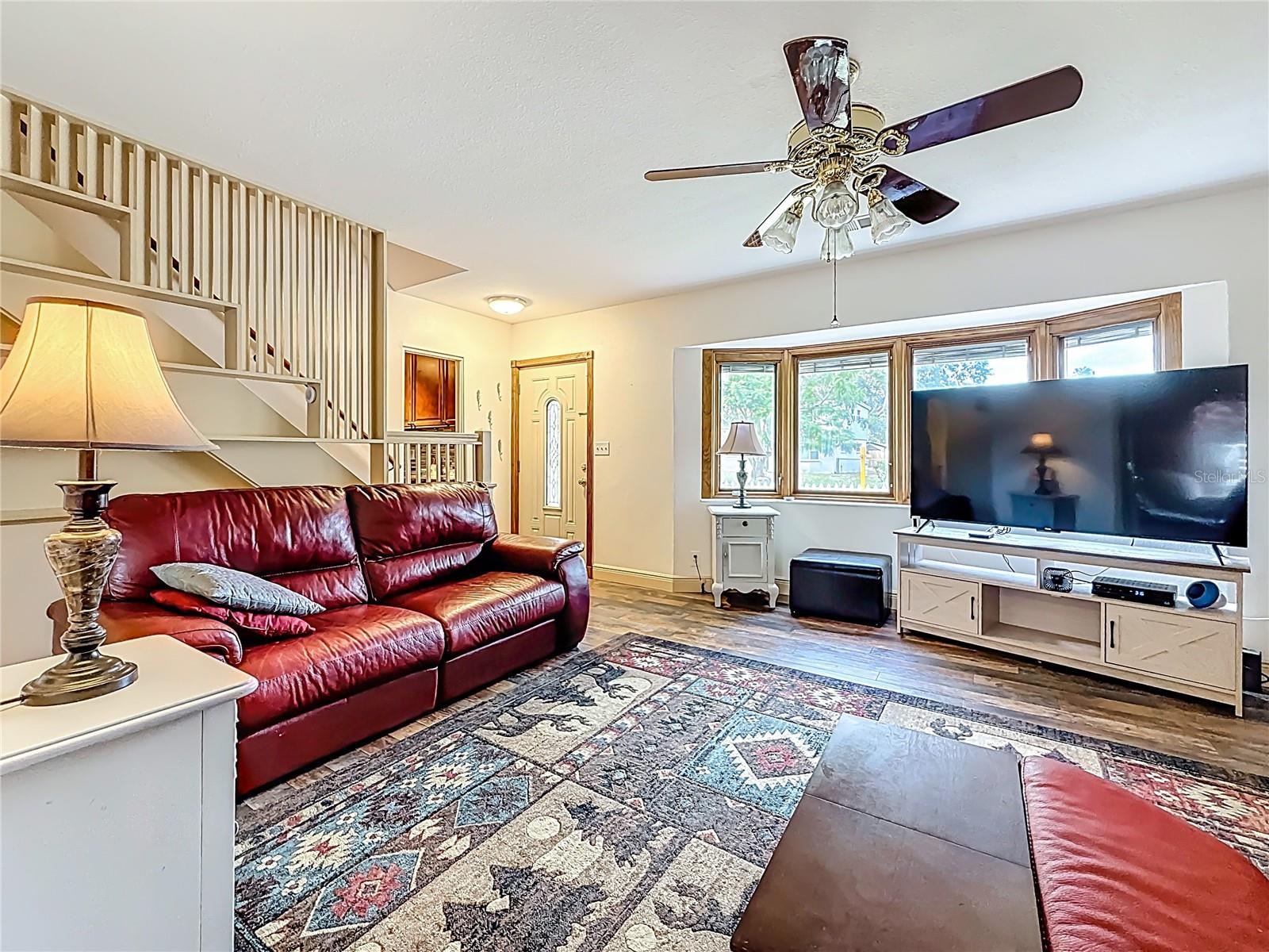 You are standing in the doorway into the 4th bedroom (currently being used as an office). View into the living room. The bay windows are Pella with built in blinds. The two outer windows open. The two center windows are stationary.  The front door is to the left of the bay windows.