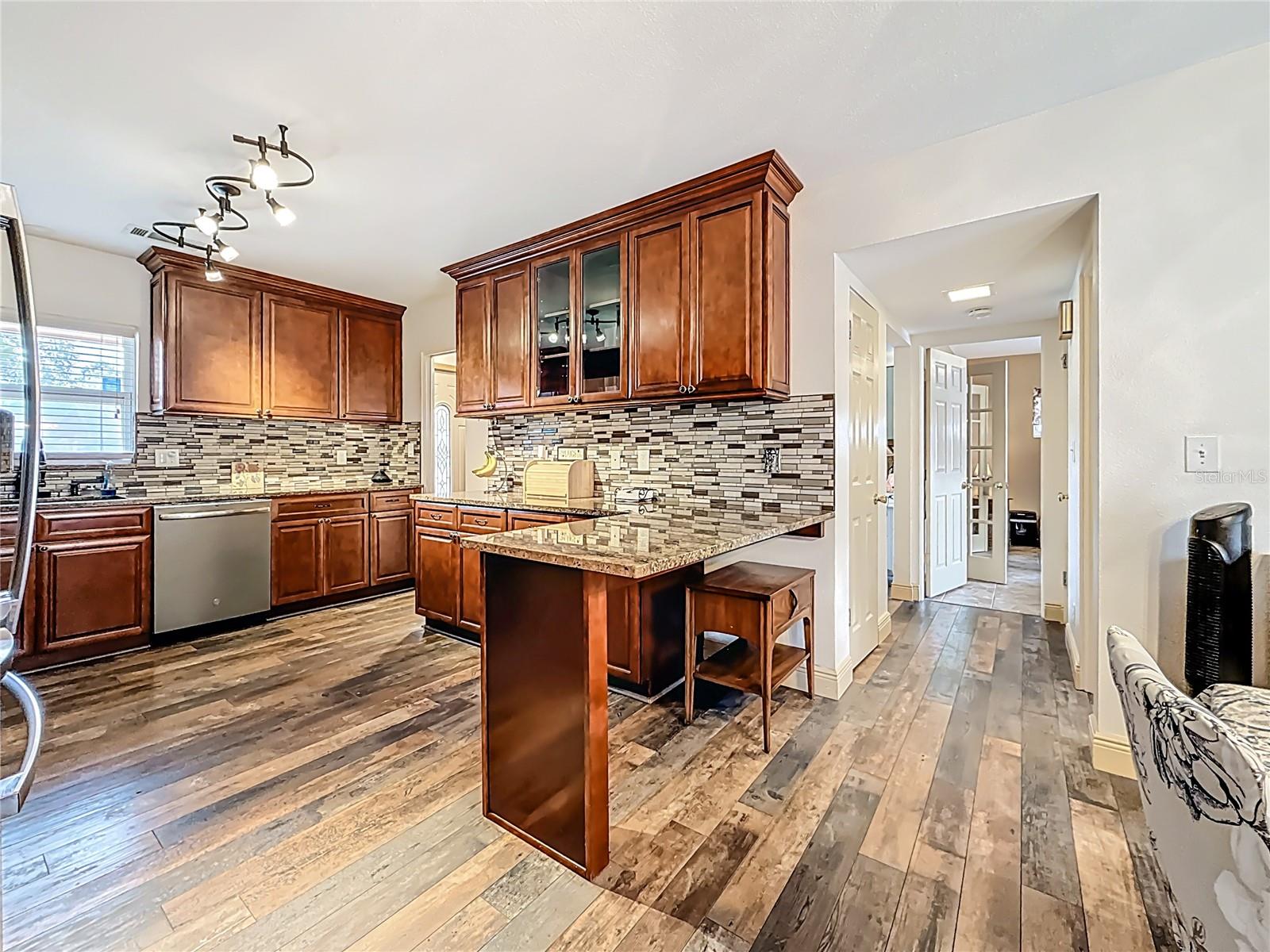 This amazing kitchen was updated in 2019. Solid wood cabinets, granite counters, glass tile backsplash. TONS of cabinets! The space under the large breakfast bar is a perfect spot for pet crates, if you wanted.